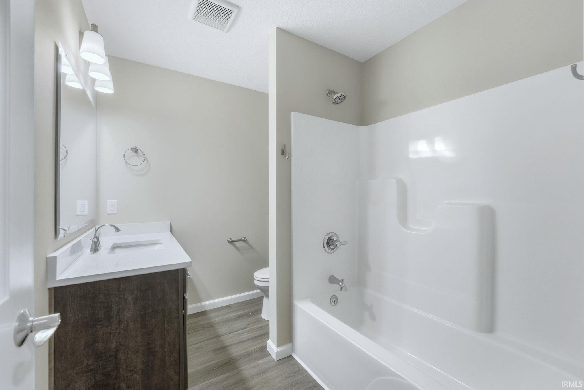 Bathroom featuring vanity, tub / shower combination, and light wood-type flooring