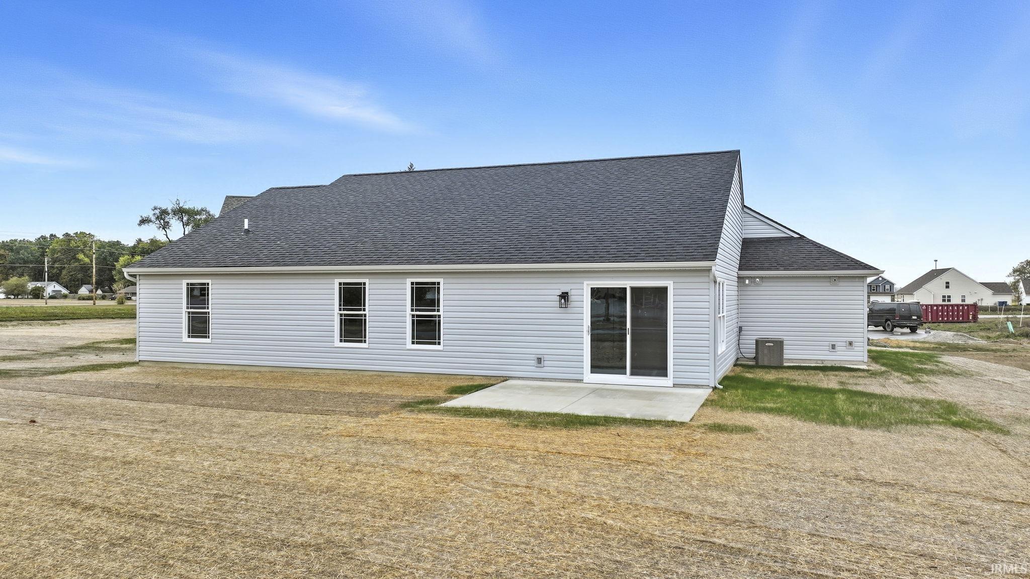 Rear view of house featuring a shingled roof and a patio area