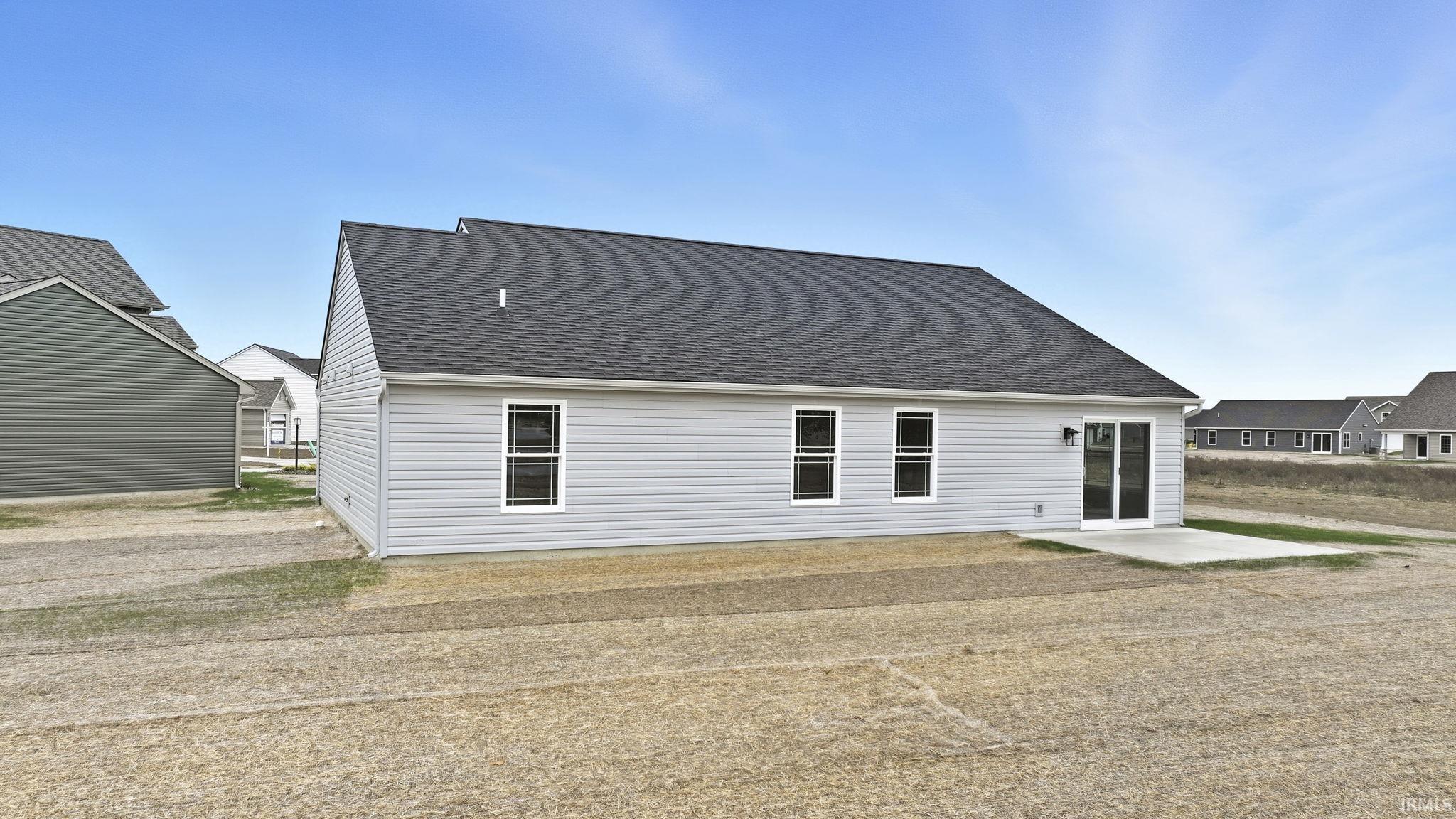 Back of property with a shingled roof and a patio