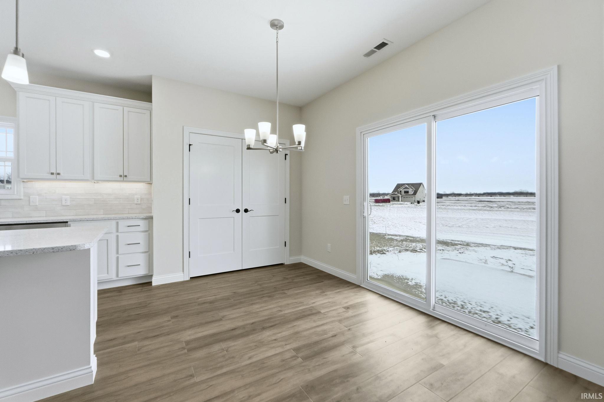 Unfurnished dining area featuring suspended lighting and light wood finished floors