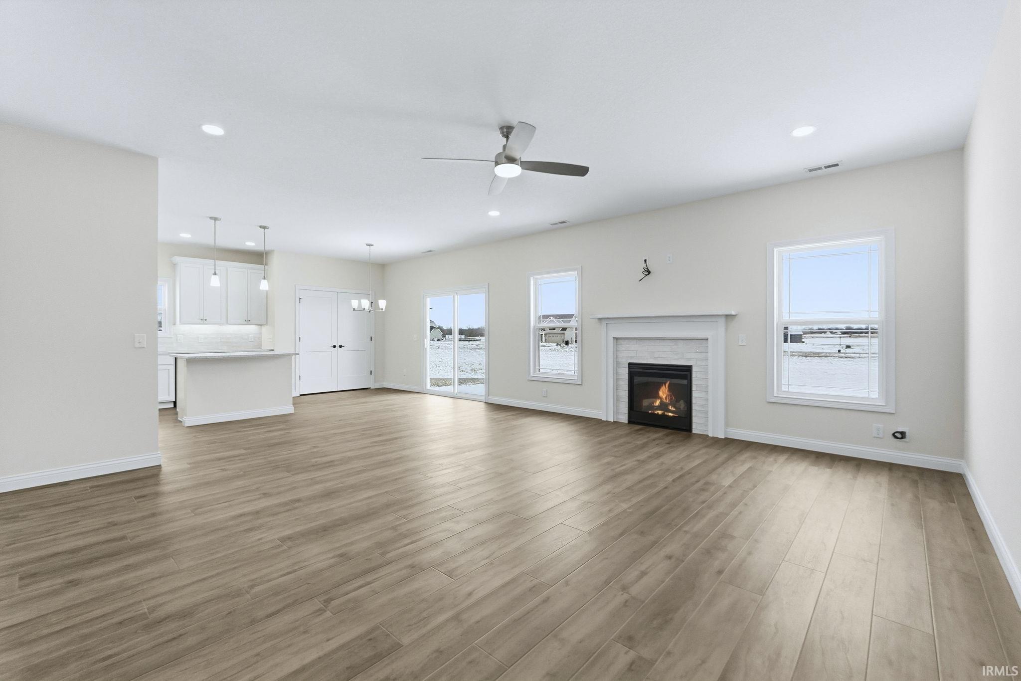 Unfurnished living room with a chandelier, light wood-style floors, a fireplace, and ceiling fan