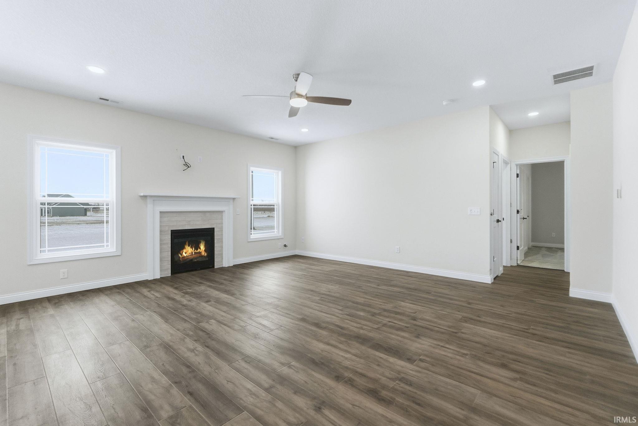 Unfurnished living room with a glass covered fireplace, a ceiling fan, dark wood finished floors, and recessed lighting