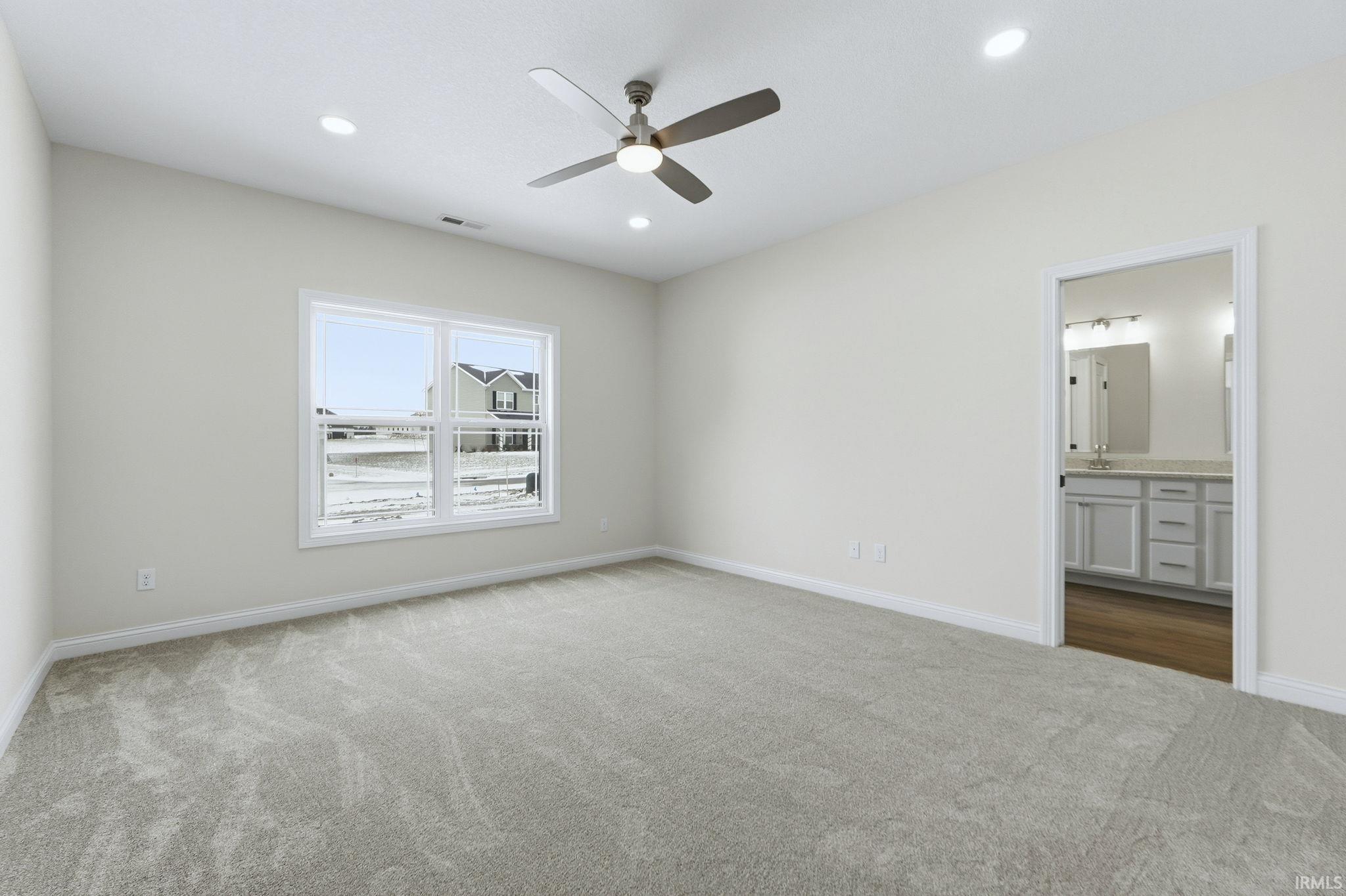 Unfurnished bedroom featuring dark colored carpet, a ceiling fan, ensuite bath, and recessed lighting