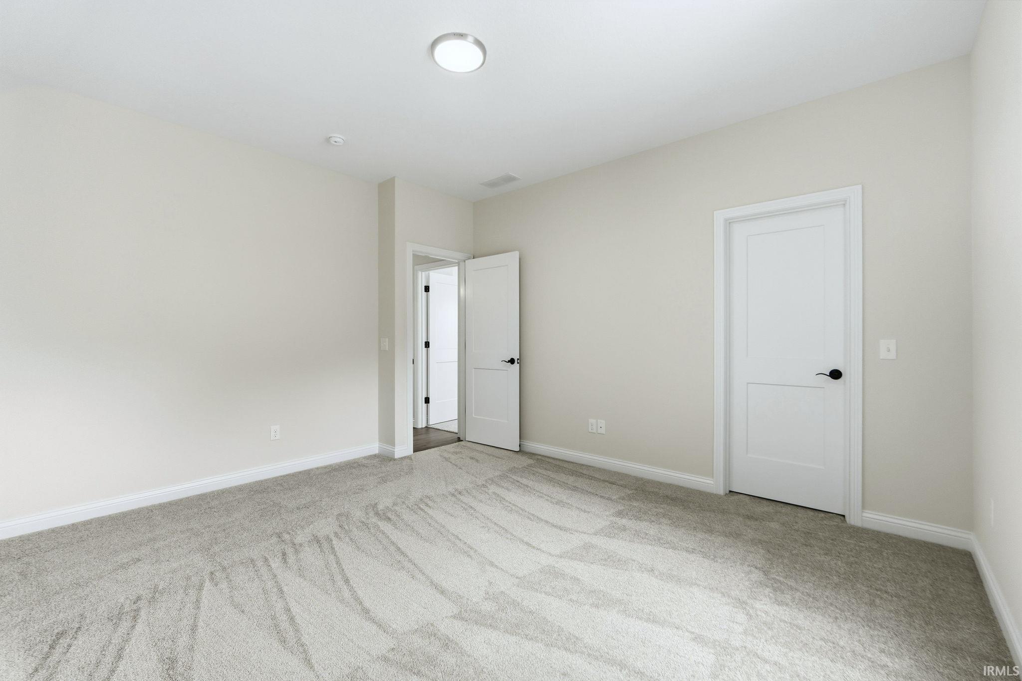 Unfurnished bedroom with light carpet and baseboards