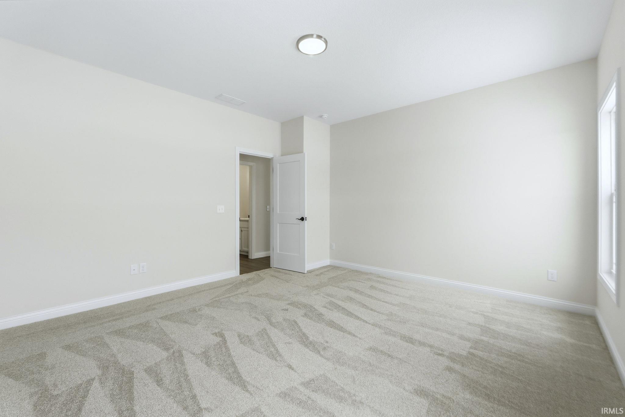 Empty room featuring light colored carpet and baseboards