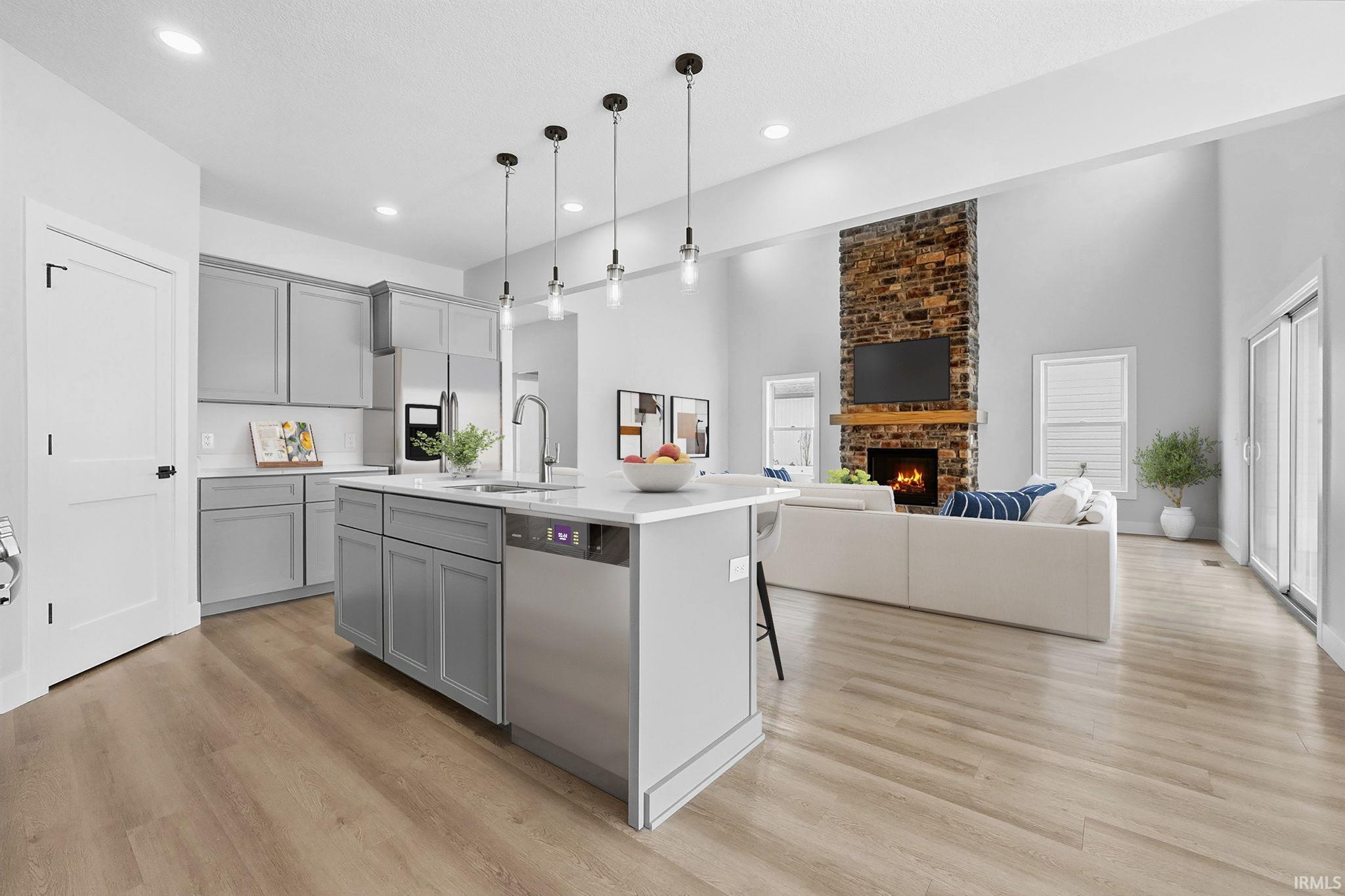 Kitchen featuring stainless steel appliances, pendant lighting, a breakfast bar area, a high ceiling, and gray cabinetry