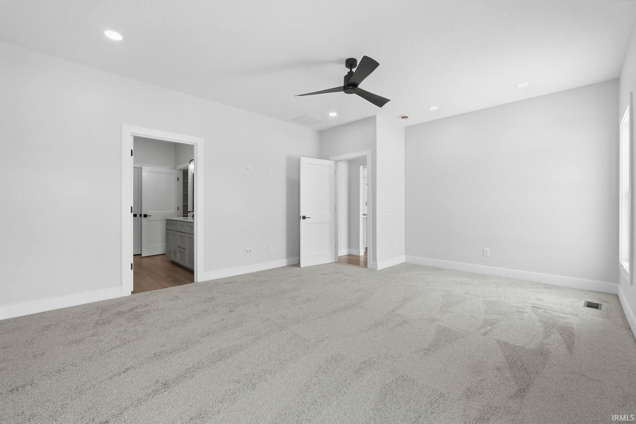 Unfurnished bedroom with light colored carpet, a ceiling fan, recessed lighting, and connected bathroom