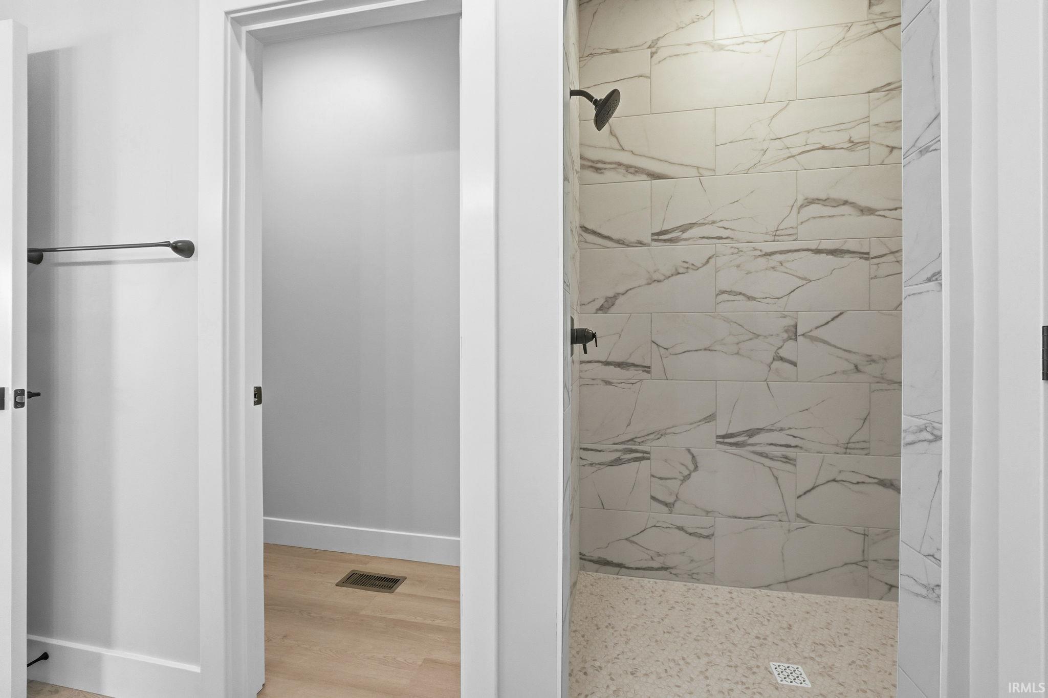 Full bath featuring a marble finish shower and light wood-type flooring