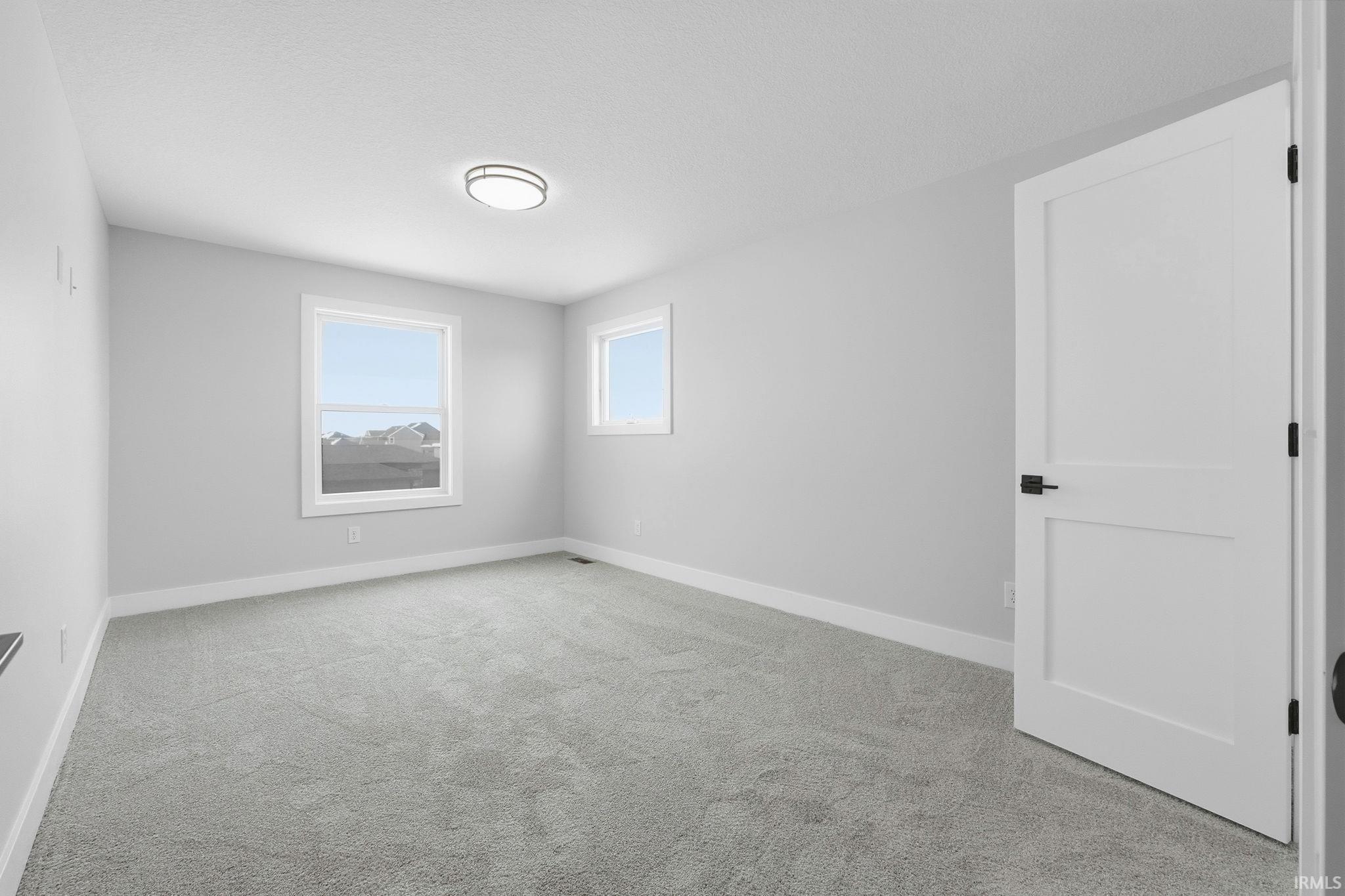 Empty room with light colored carpet and baseboards