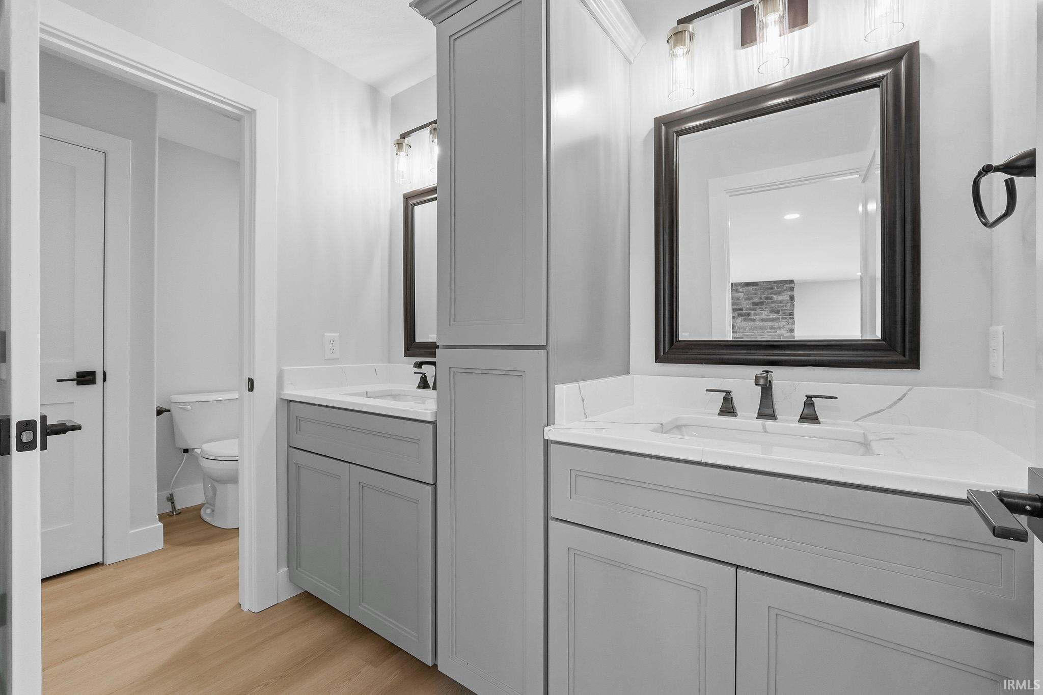 Full bathroom with two vanities and light wood-style flooring