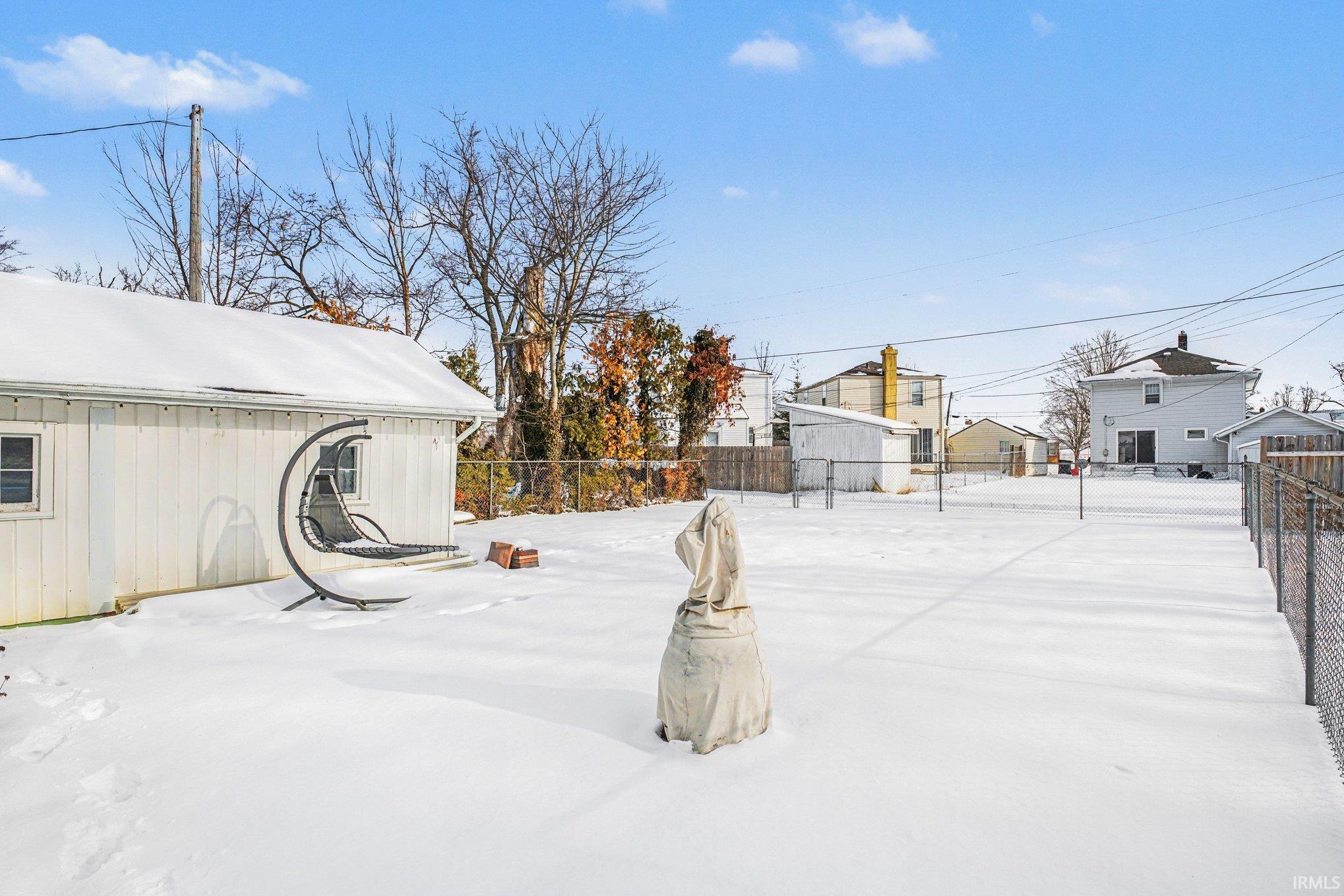 Yard covered in snow featuring a fenced backyard and an outdoor structure
