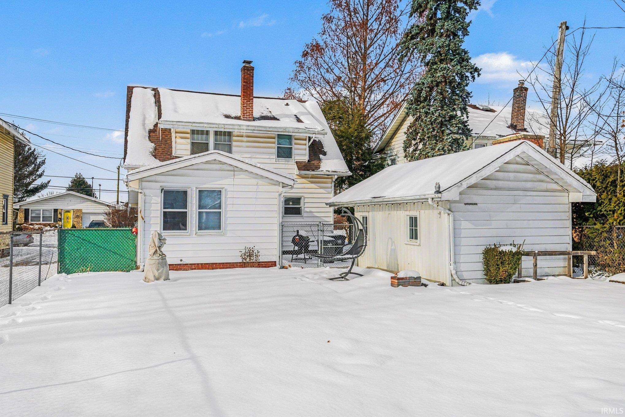 Snow covered property featuring a chimney and an outdoor structure