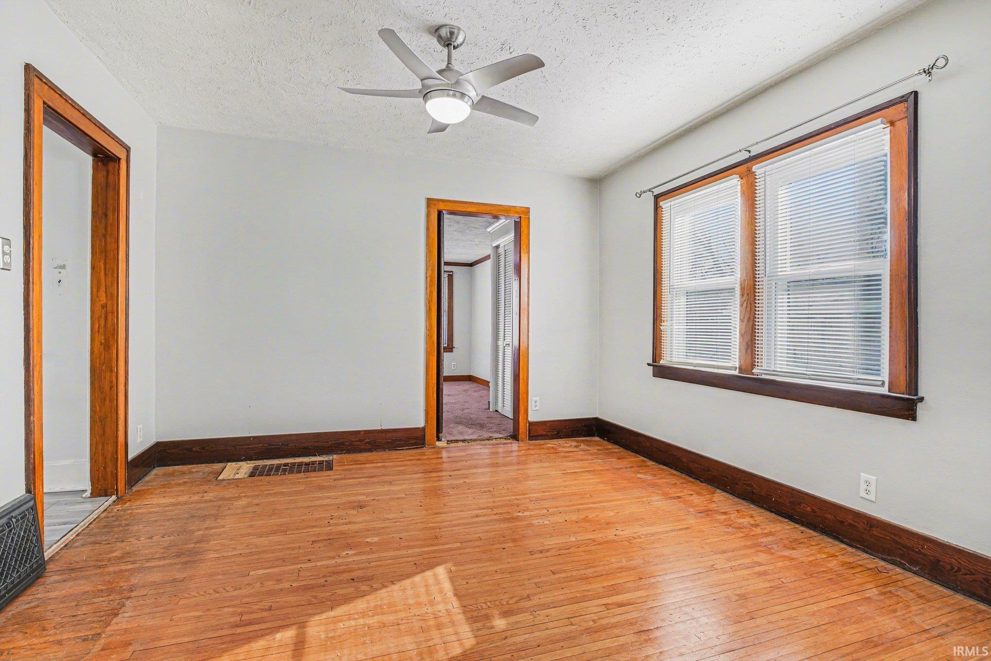 featuring hardwood / wood-style flooring, a textured ceiling, and ceiling fan