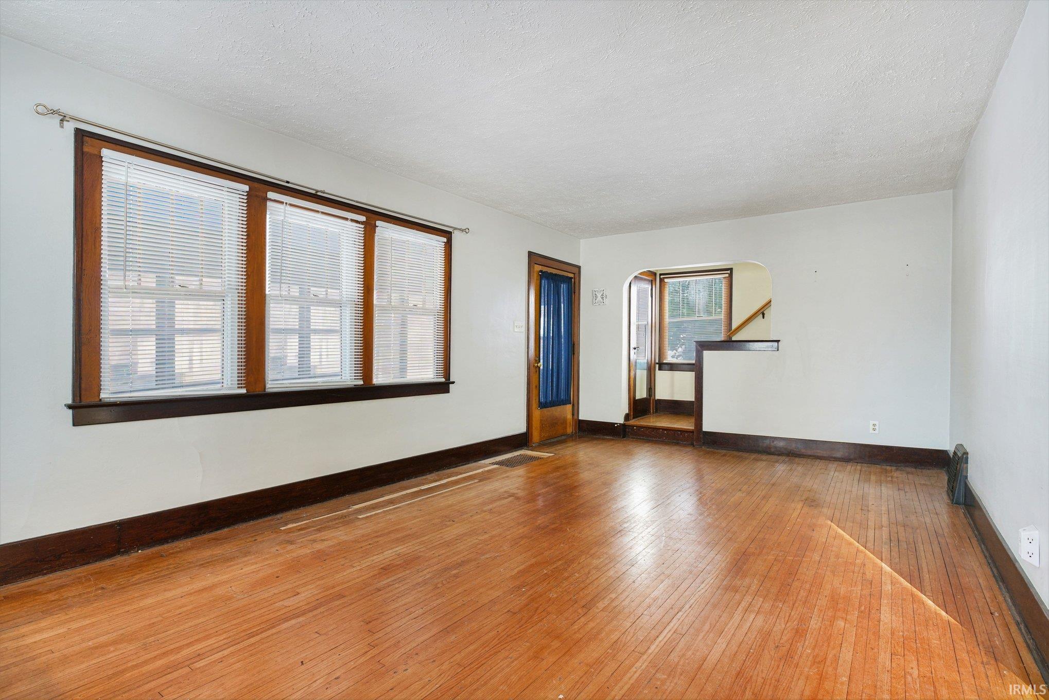 with hardwood / wood-style floors, arched walkways, and a textured ceiling