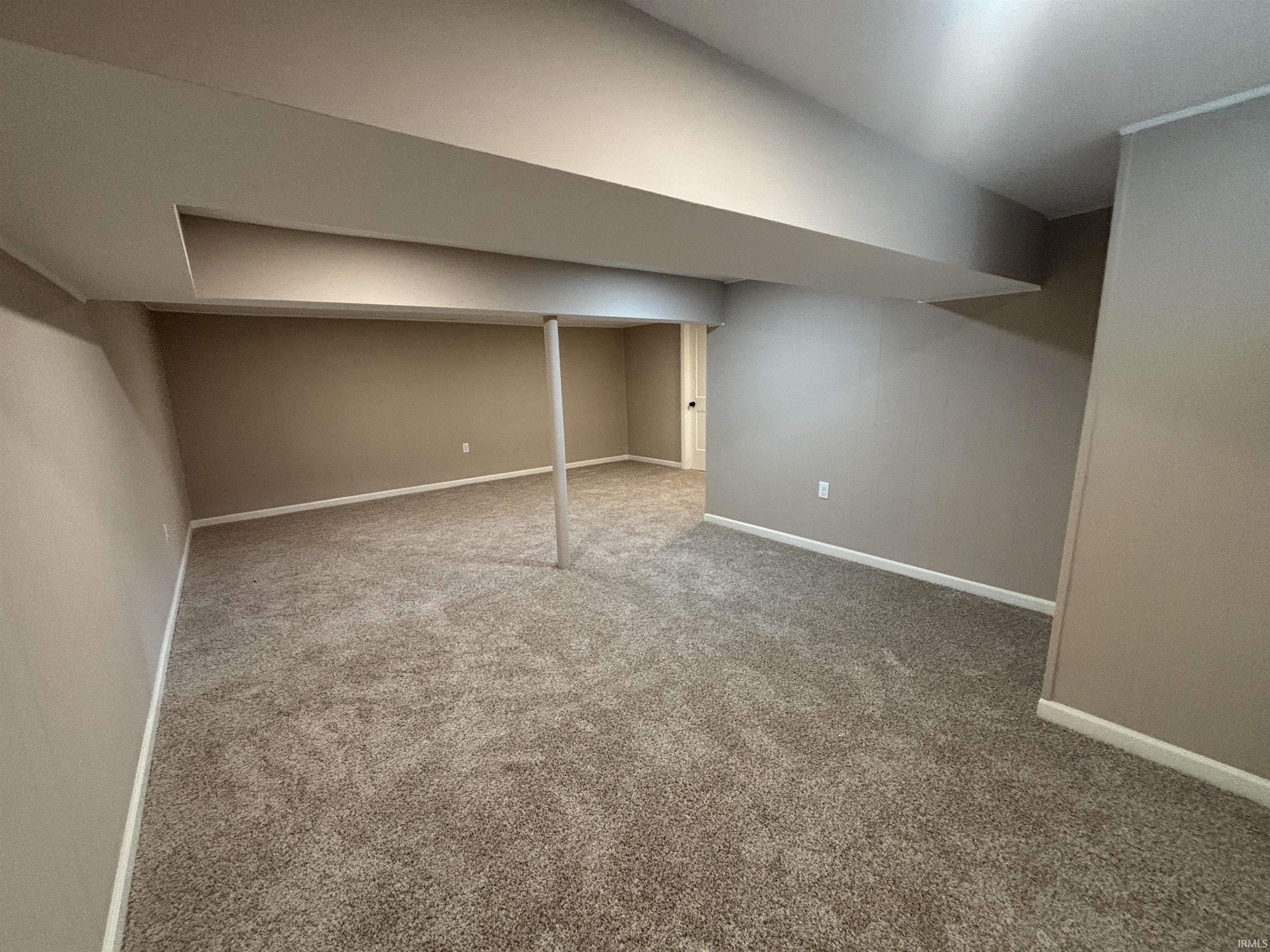 Finished below grade area featuring baseboards and light carpet