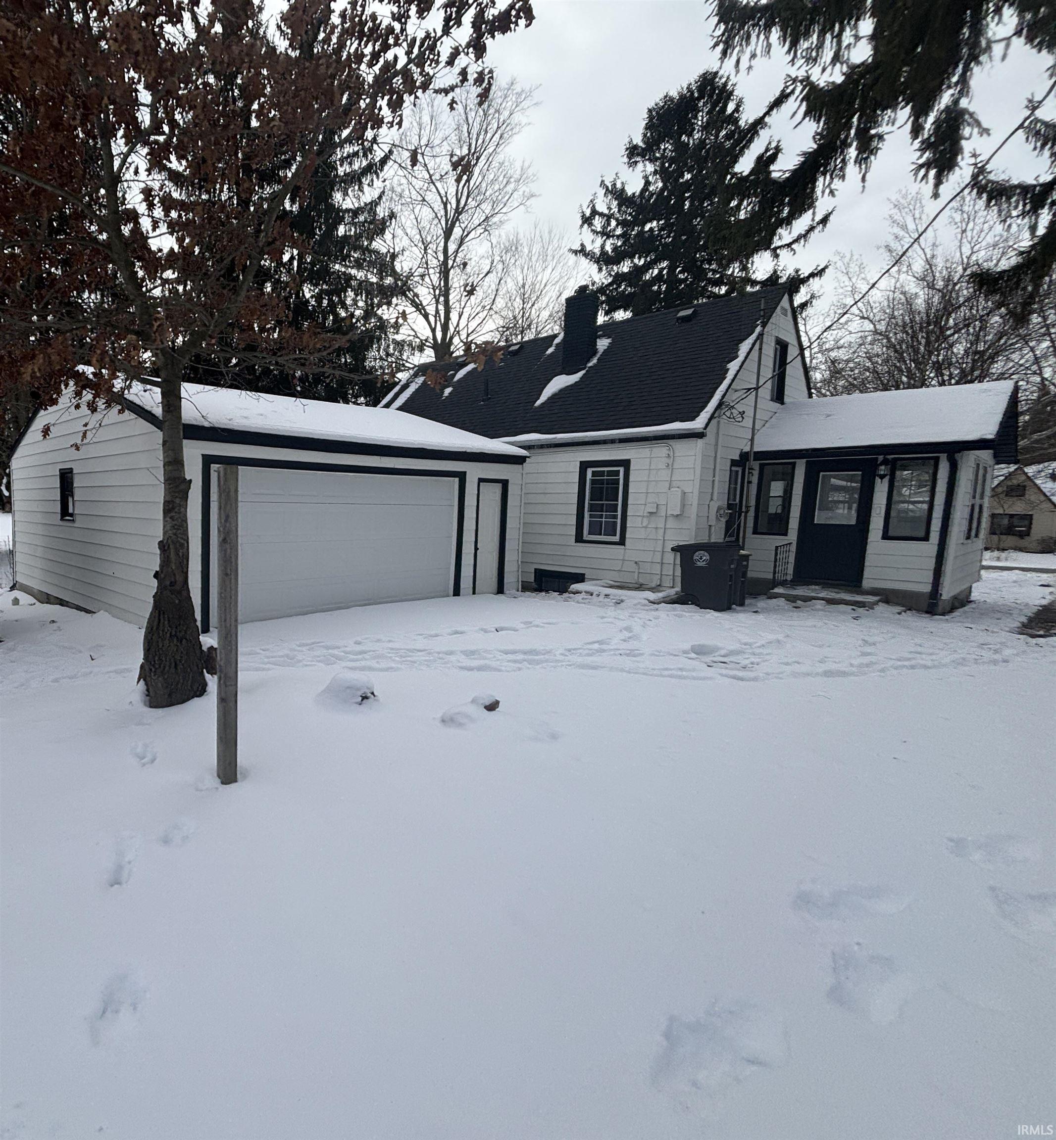 View of front of home featuring an outdoor structure, a garage, and a chimney