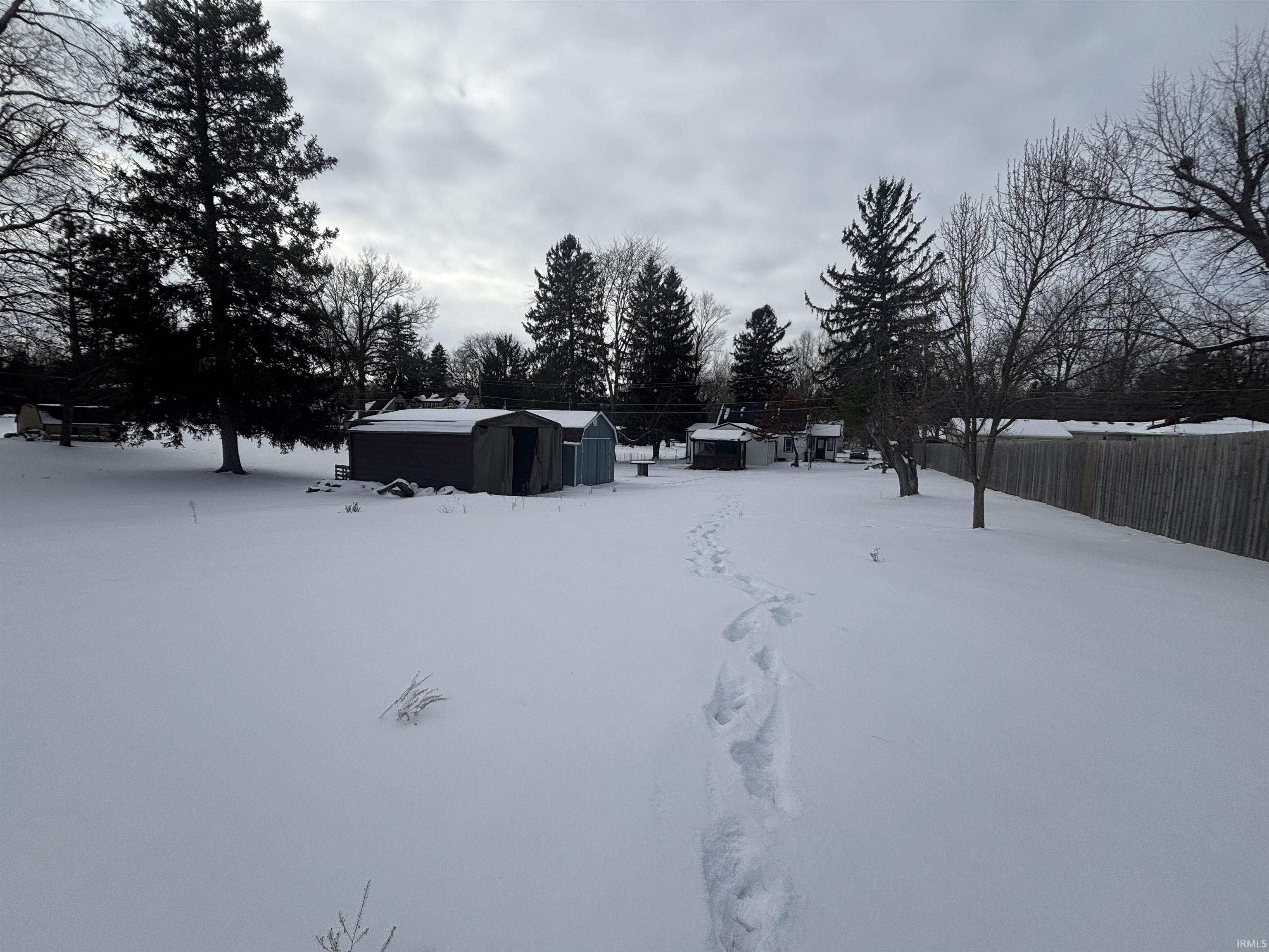 Yard covered in snow featuring a storage unit