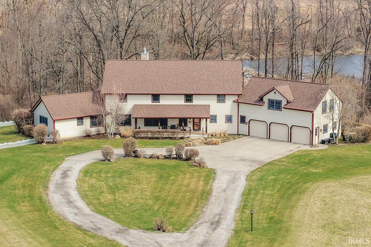 View of front of home with driveway, a front lawn, a water view, a chimney, and roof with shingles