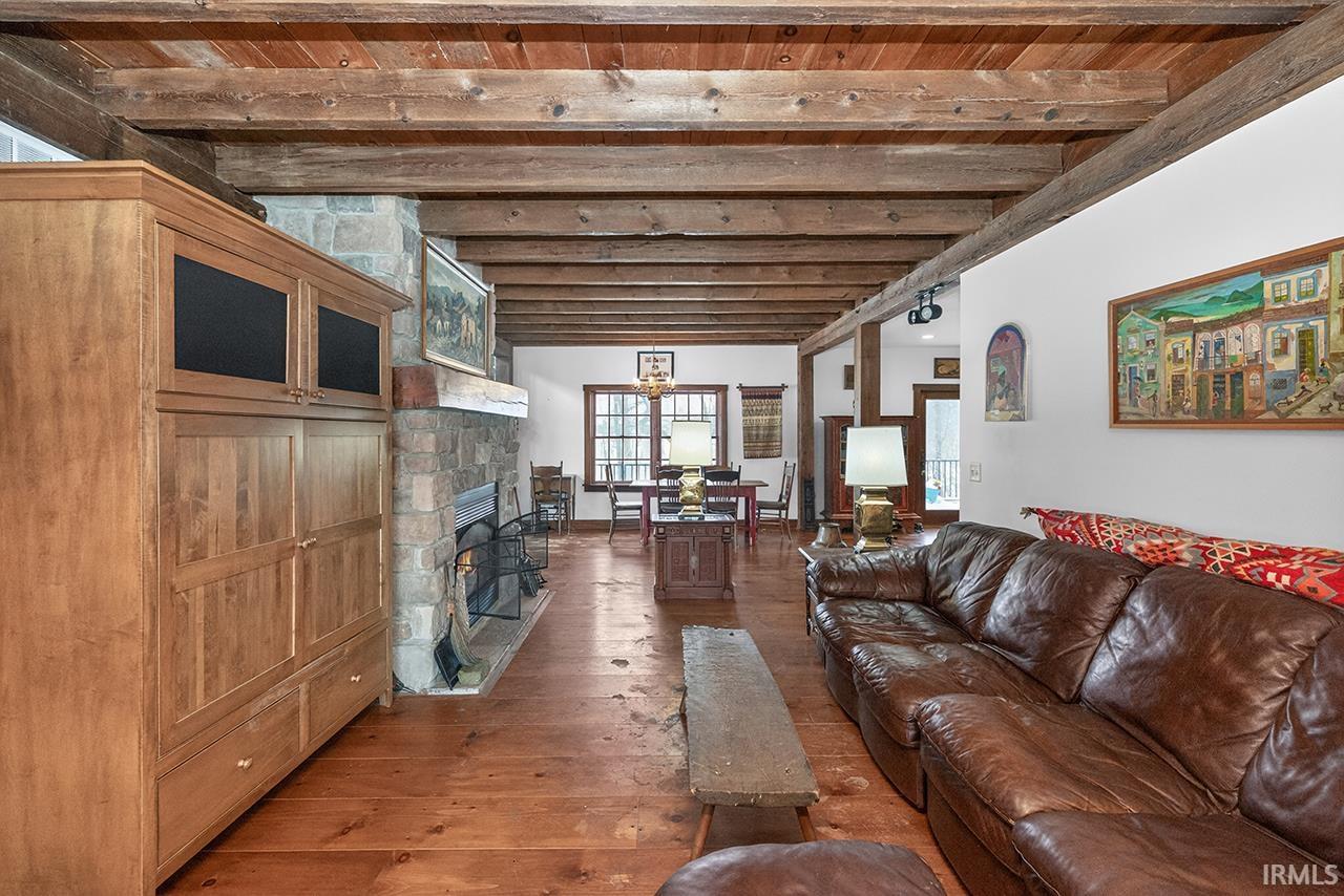 Living area featuring dark wood-style floors, healthy amount of natural light, a wooden ceiling with exposed beams, and a fireplace