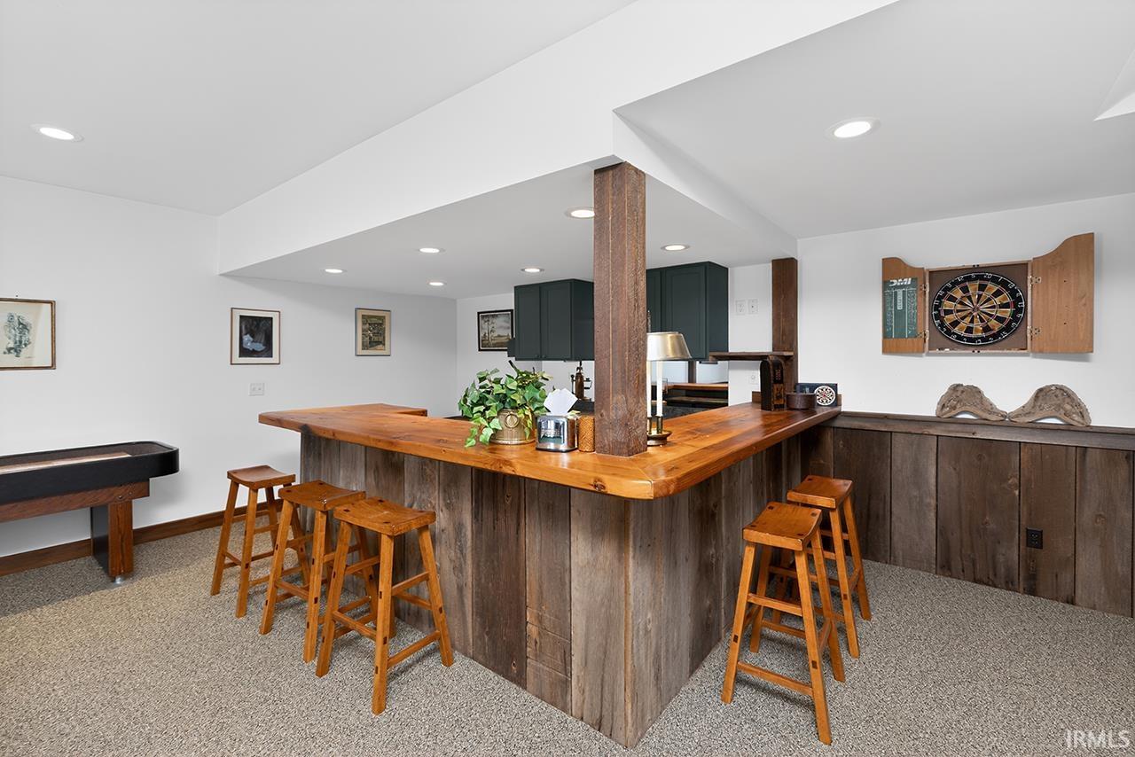 Indoor dry bar with butcher block counters, light colored carpet, and recessed lighting