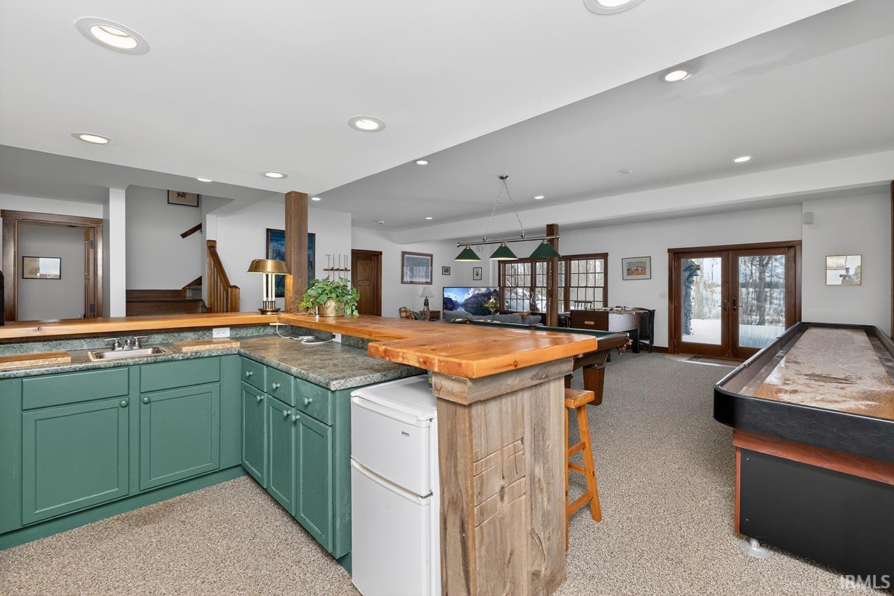 Kitchen with french doors, wooden counters, open floor plan, a kitchen breakfast bar, and green cabinets