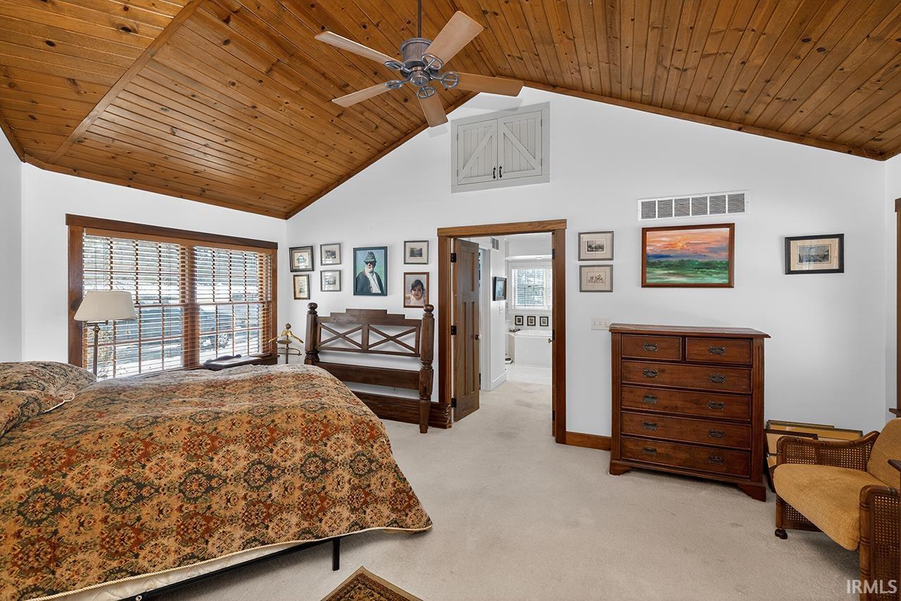 Bedroom with light colored carpet, a high wood ceiling, and ceiling fan