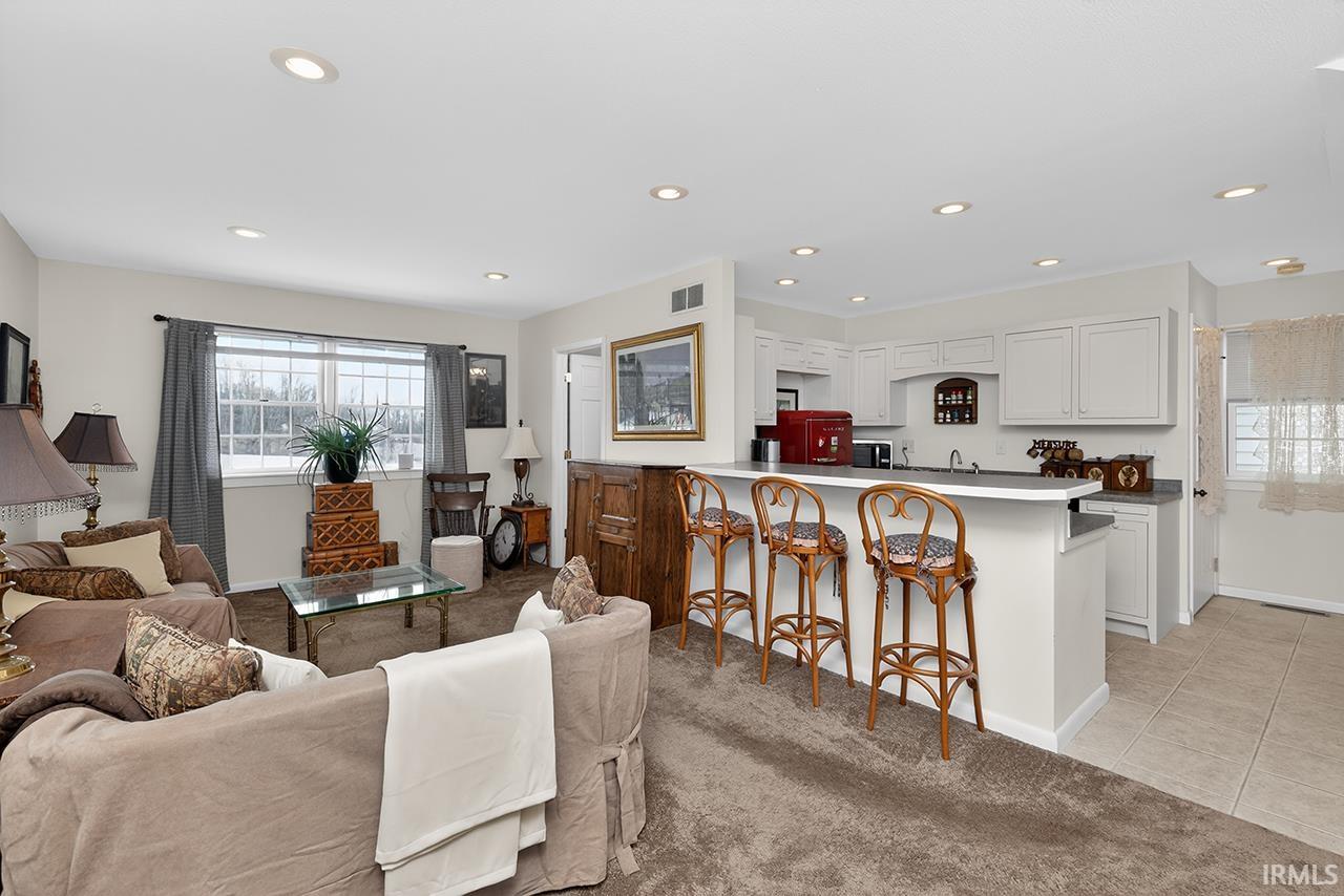 Living area featuring light colored carpet, light tile patterned flooring, and recessed lighting