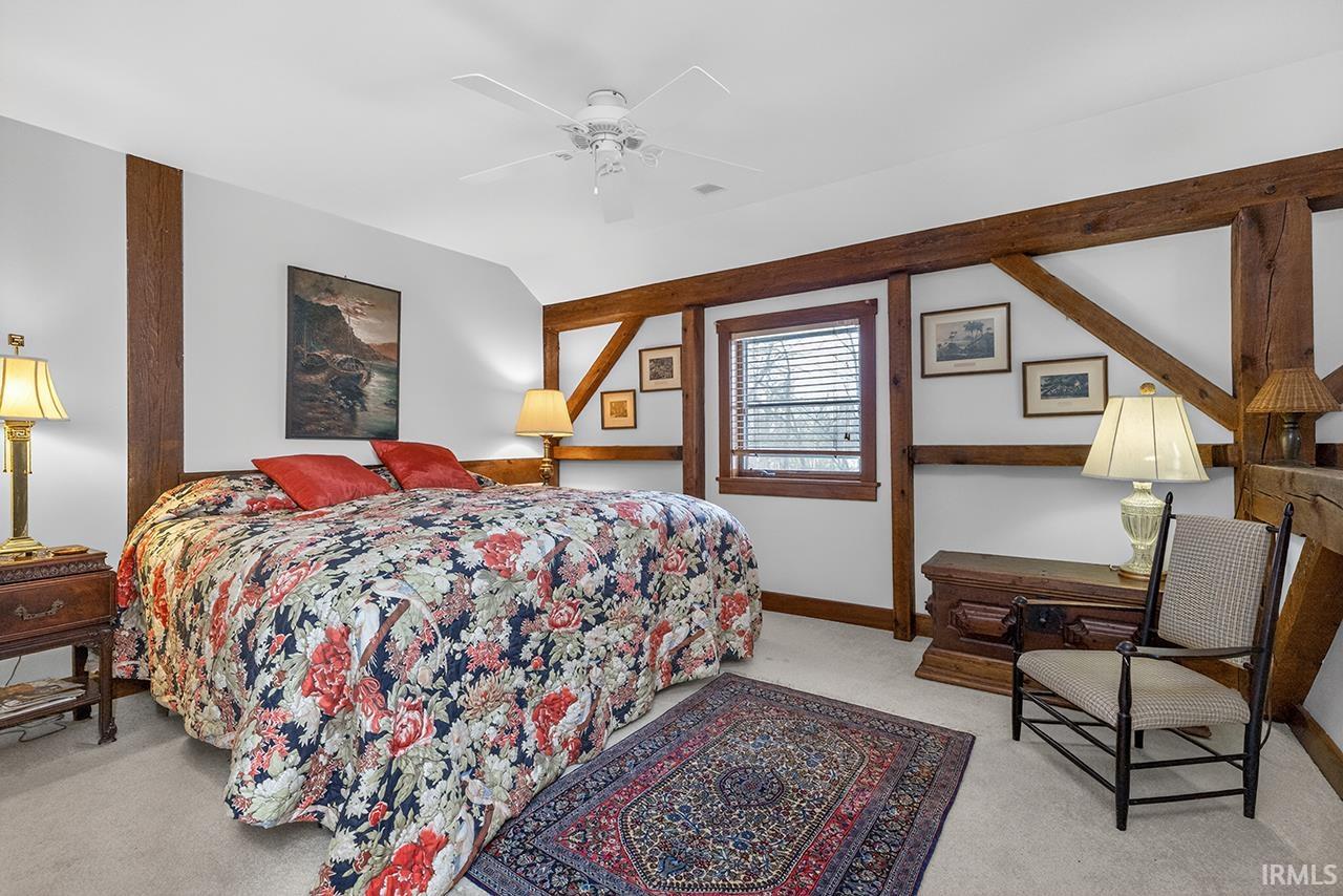 Bedroom with vaulted ceiling, light colored carpet, and ceiling fan