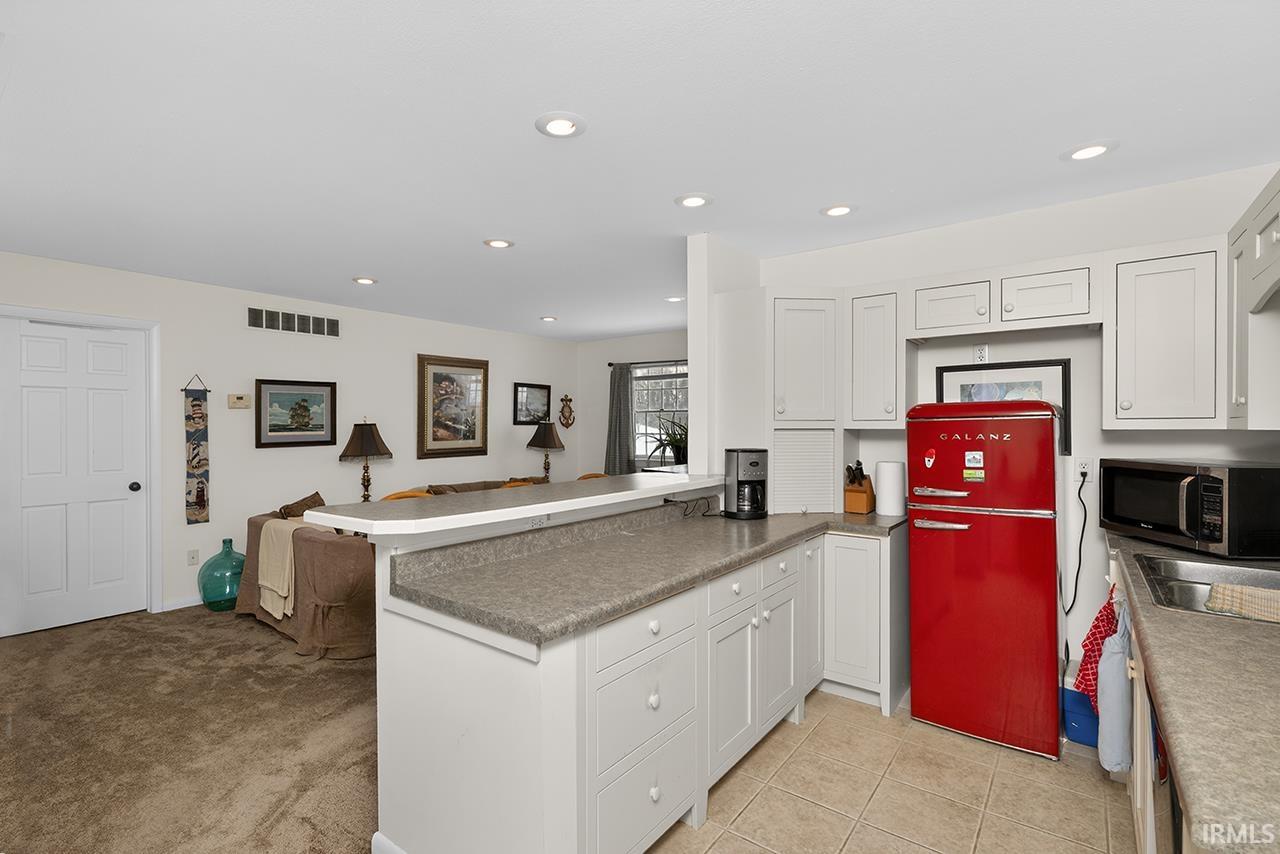 Kitchen featuring open floor plan, freestanding refrigerator, white cabinetry, and recessed lighting