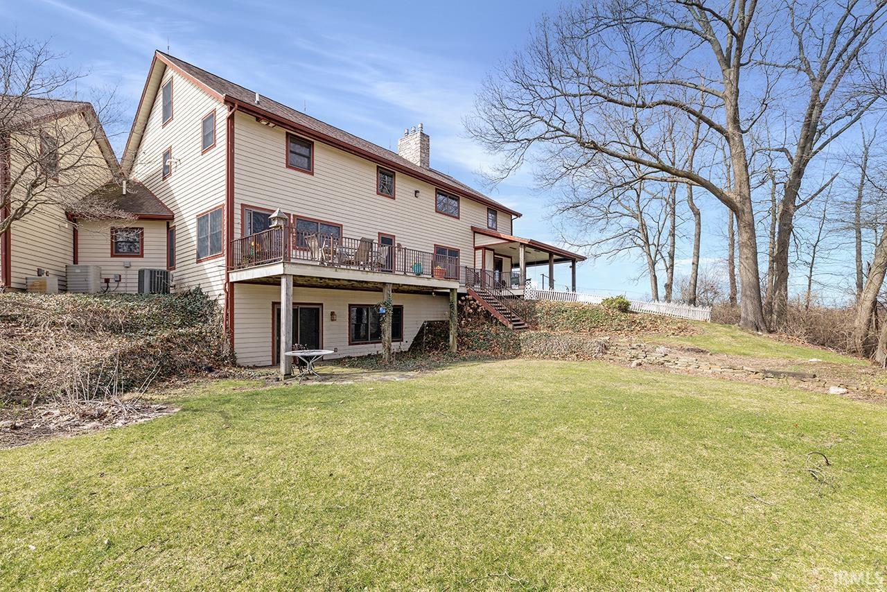 Back of property featuring a chimney, a lawn, and a deck