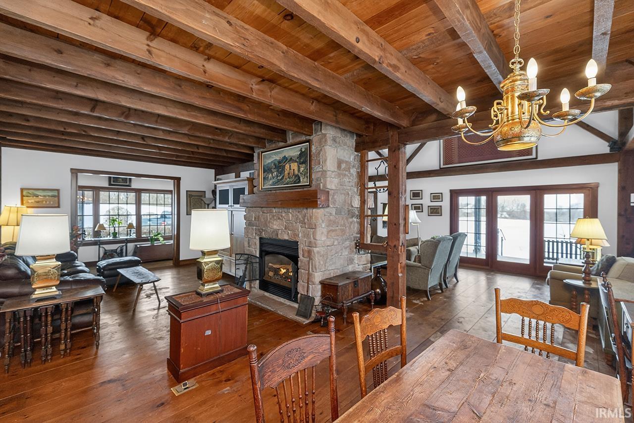 Living area with hardwood / wood-style flooring, a fireplace, hanging lights, french doors, and a wood ceiling with exposed beams