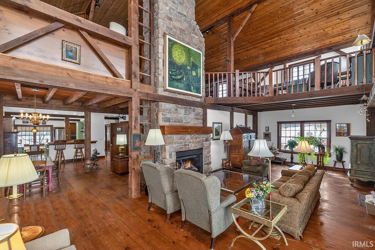 Living area with a fireplace, a high wooden beamed ceiling, hardwood / wood-style flooring, and hanging lights