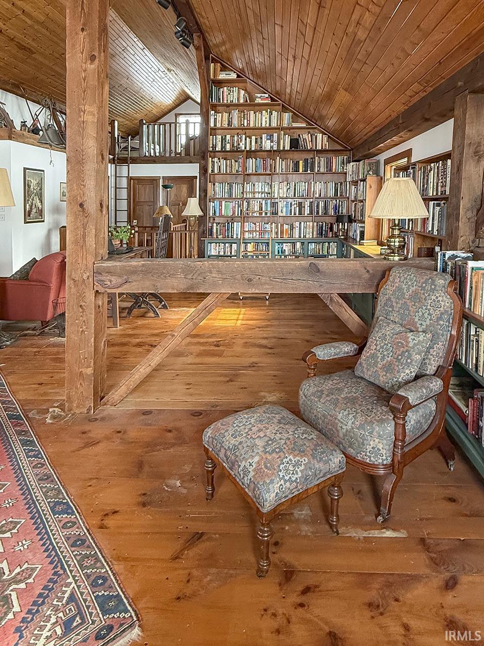 Living area with hardwood / wood-style floors, a vaulted wood ceiling, and bookshelves