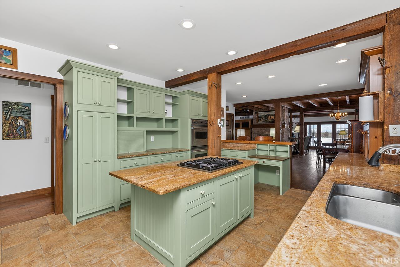 Kitchen with light stone counters, beam ceiling, a center island, stainless steel appliances, and open shelves