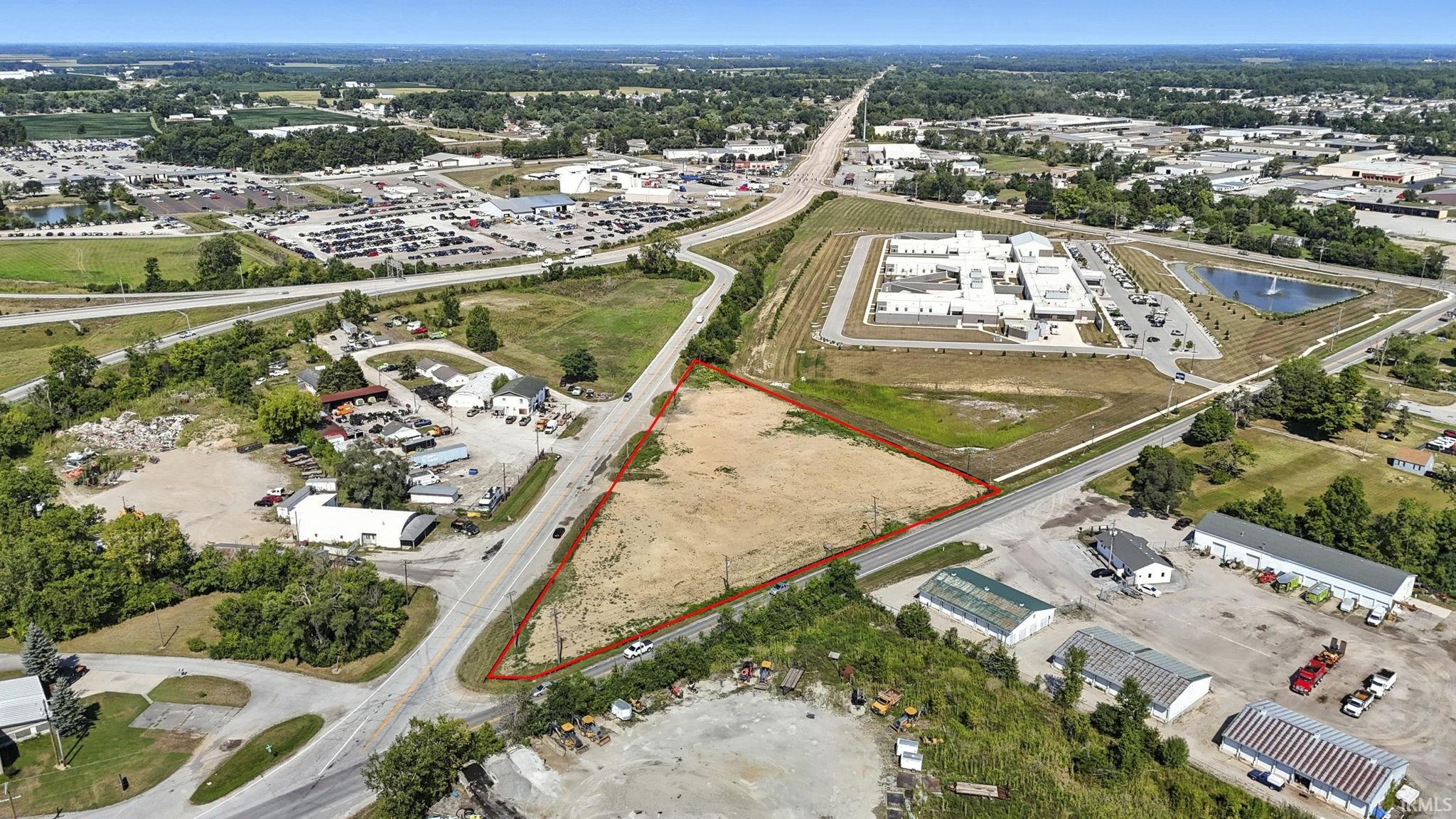 Aerial view of property and surrounding area with property parcel outlined and a large body of water