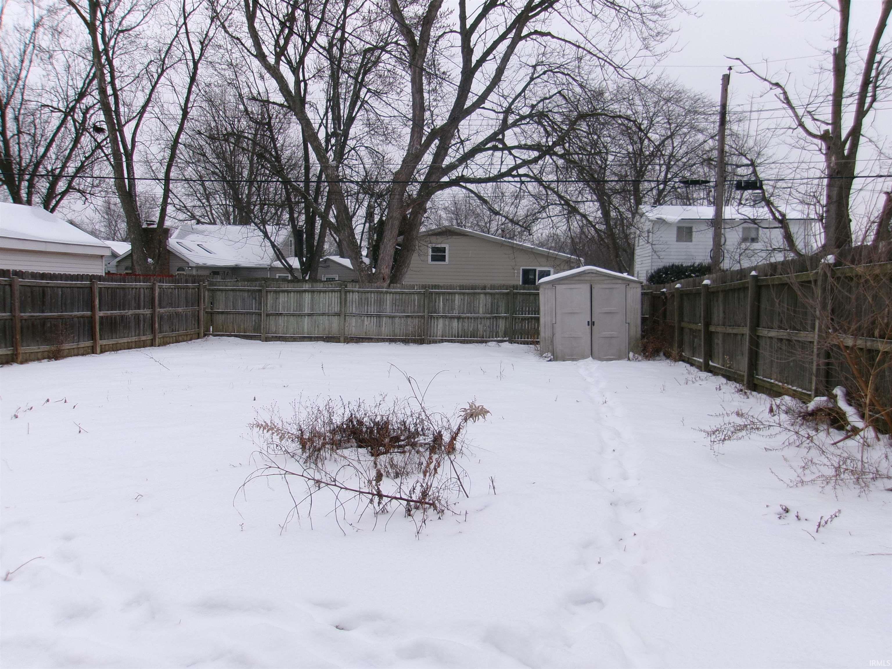 Yard layered in snow featuring a shed and a fenced backyard