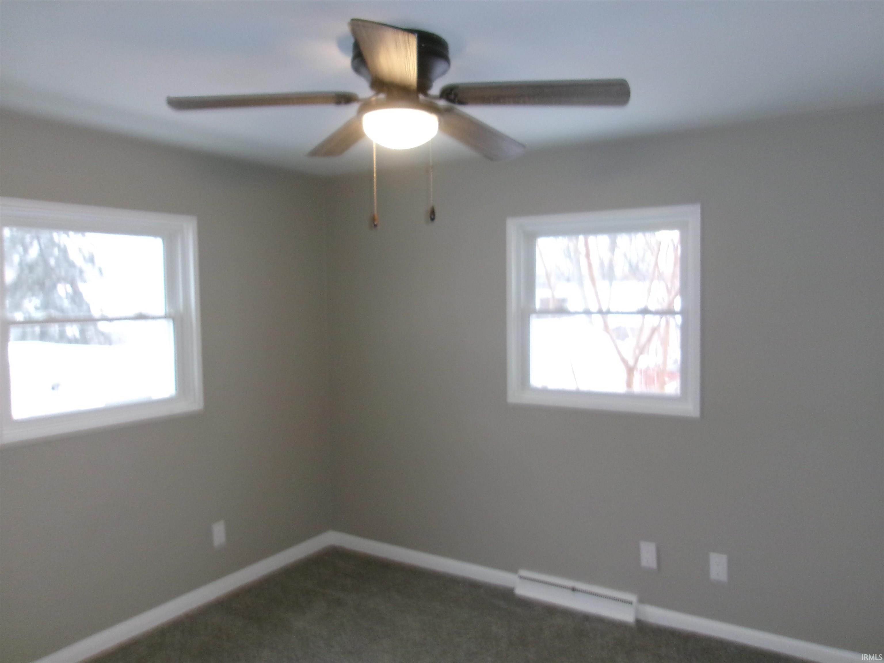 Unfurnished room featuring dark carpet and ceiling fan