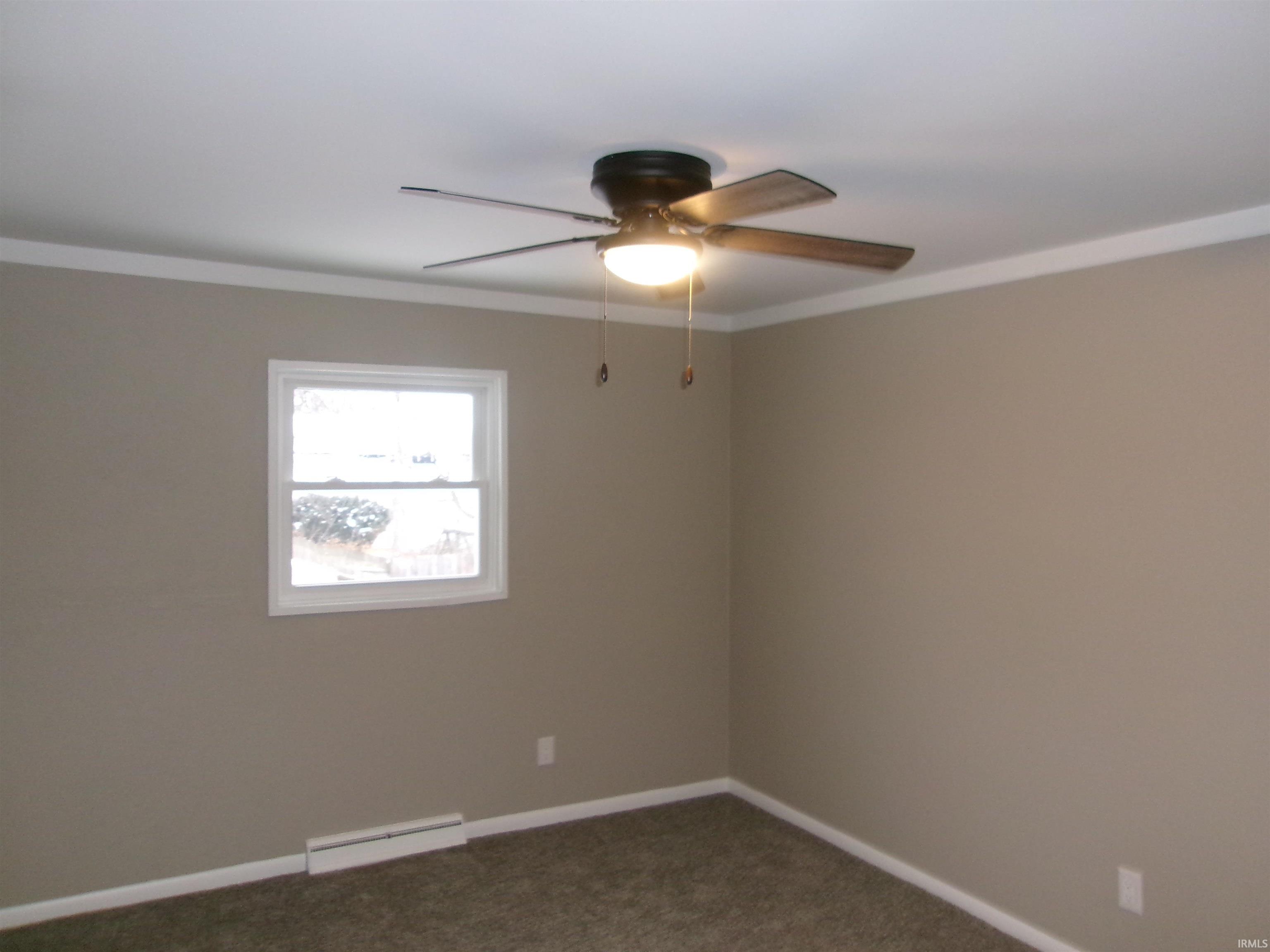 Spare room with crown molding, dark carpet, ceiling fan, and a baseboard heating unit