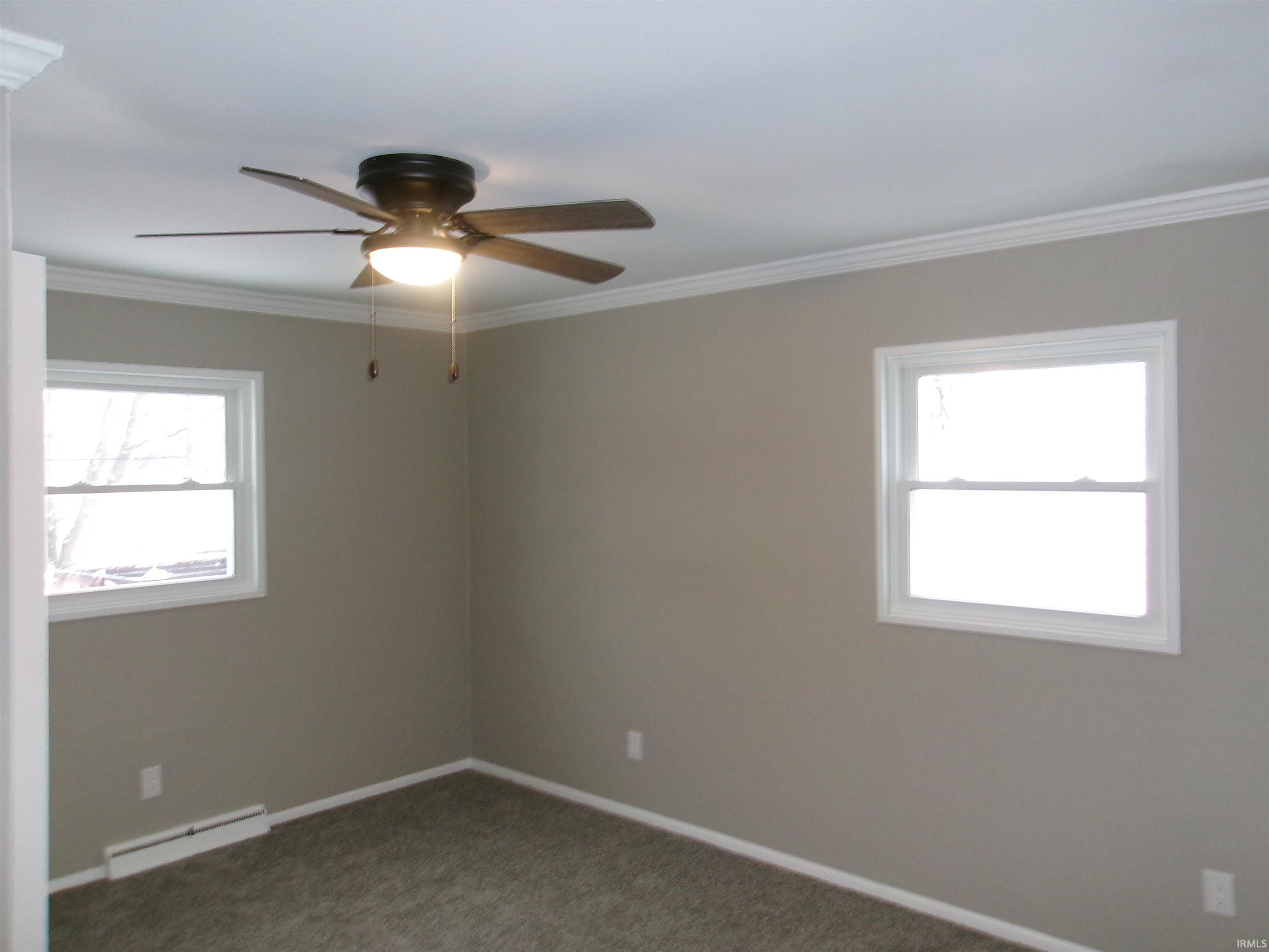 Spare room with crown molding, a ceiling fan, carpet flooring, and a baseboard heating unit