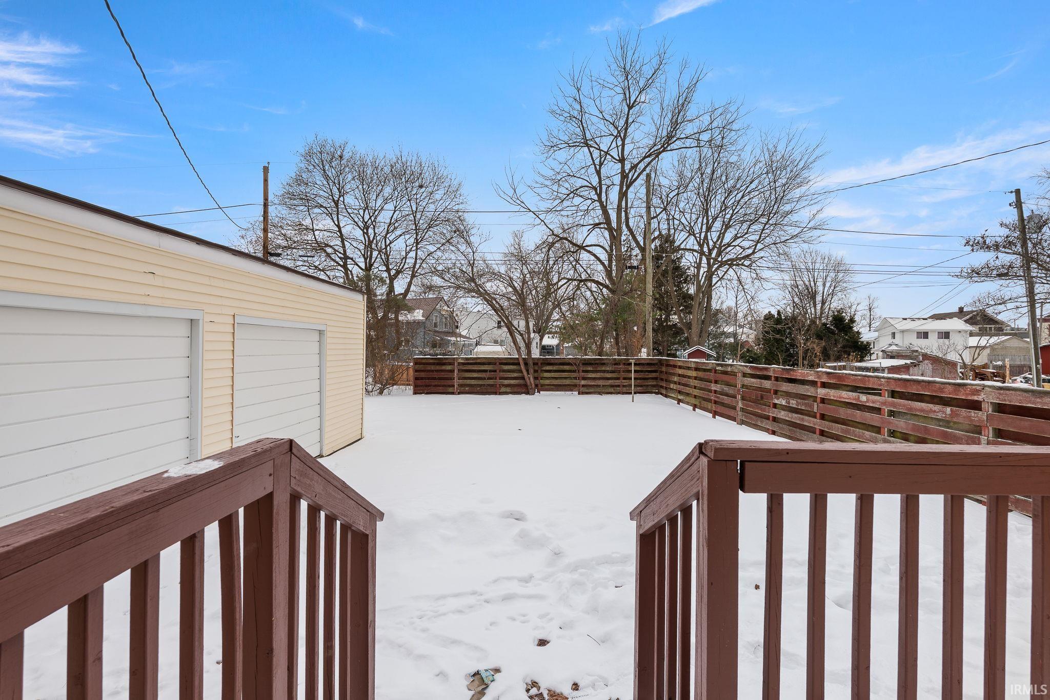 Snowy yard featuring a deck and a residential view