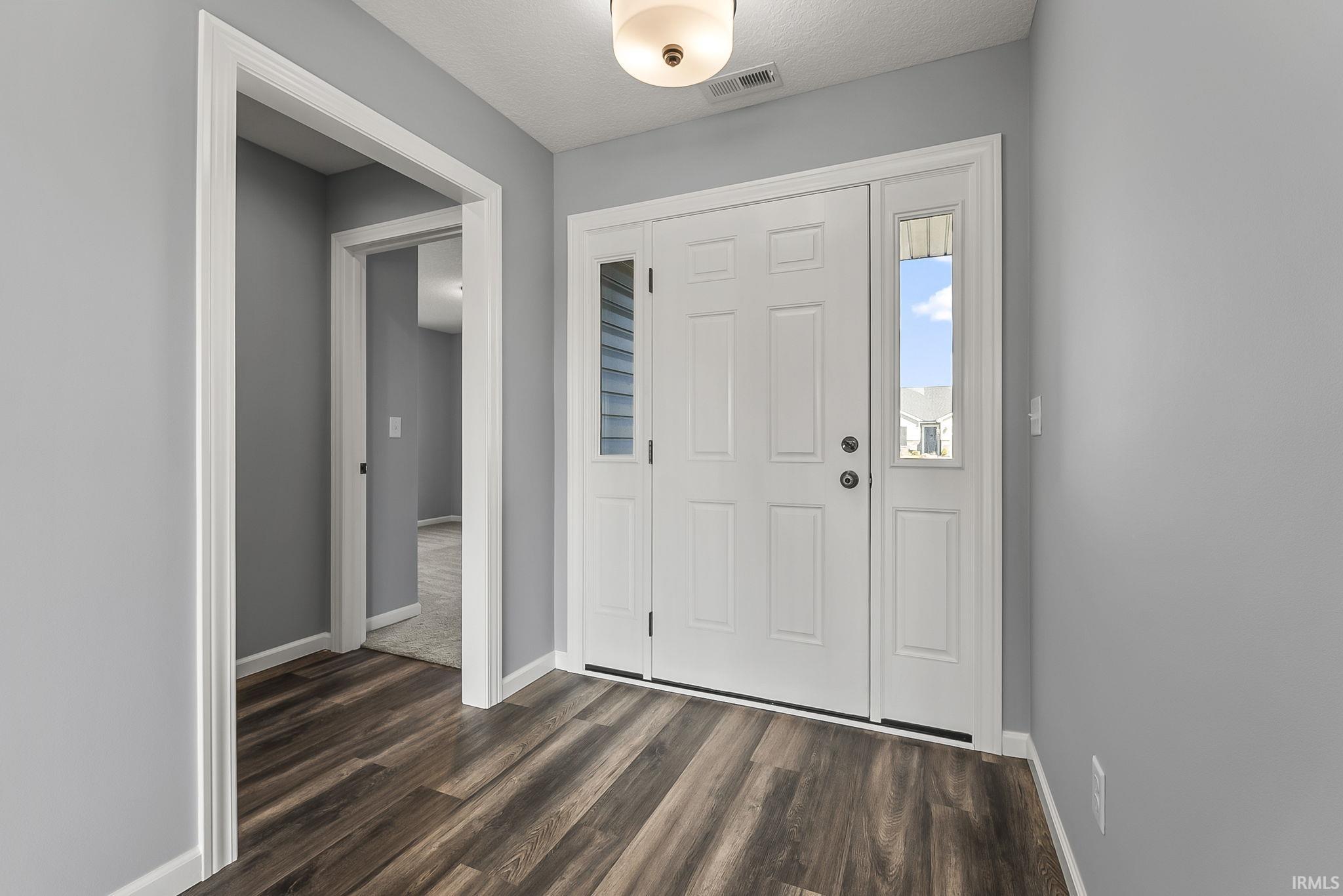 Foyer entrance featuring baseboards and dark wood-style floors
