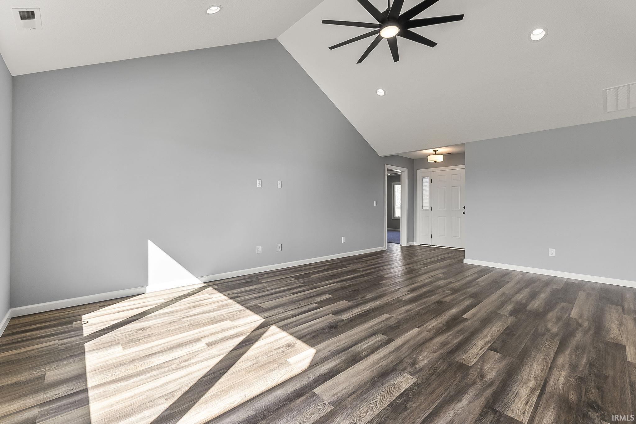 Unfurnished living room with a high ceiling, ceiling fan, recessed lighting, and dark wood-style floors