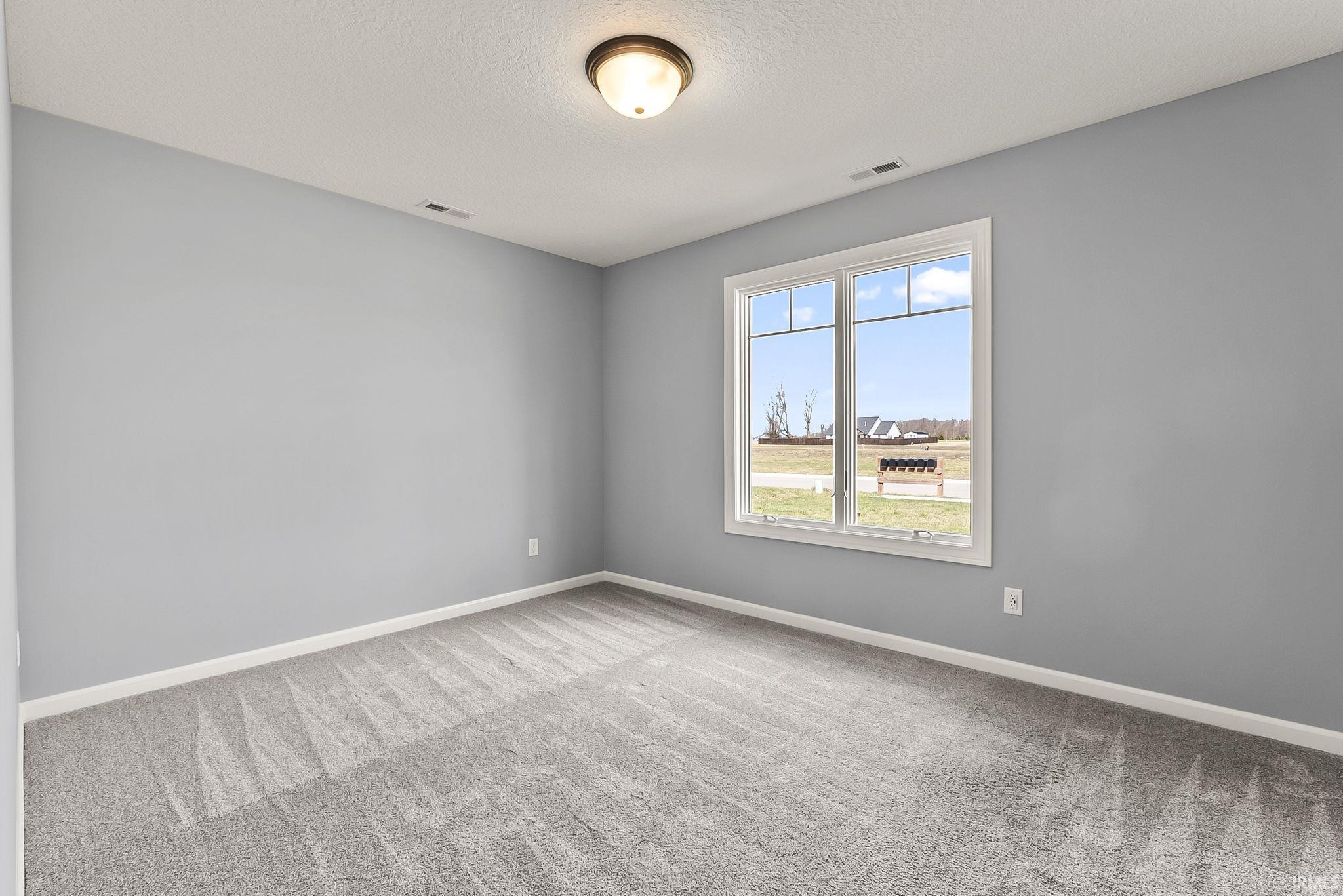 Unfurnished room featuring light colored carpet and a textured ceiling
