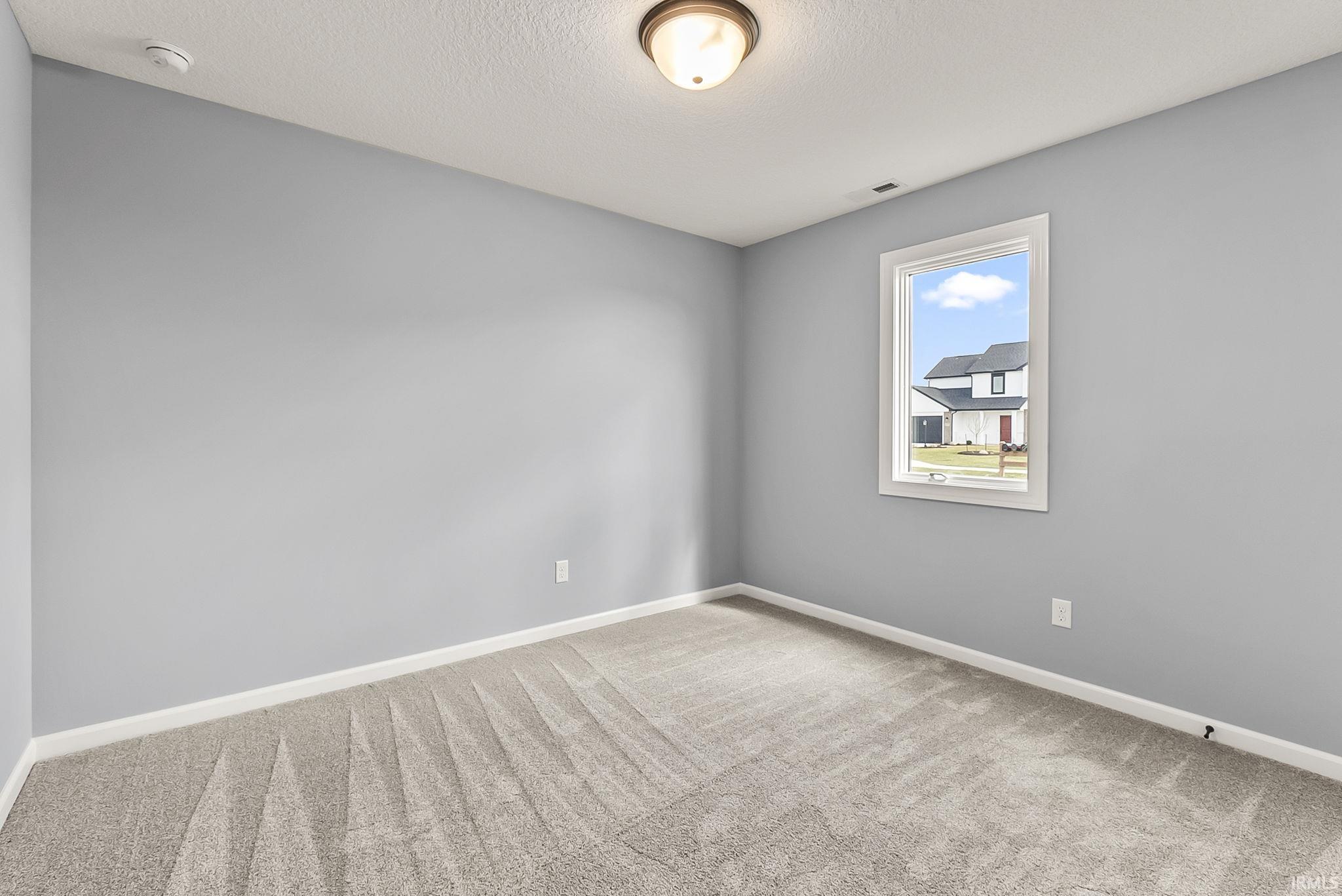 Empty room featuring light carpet and a textured ceiling