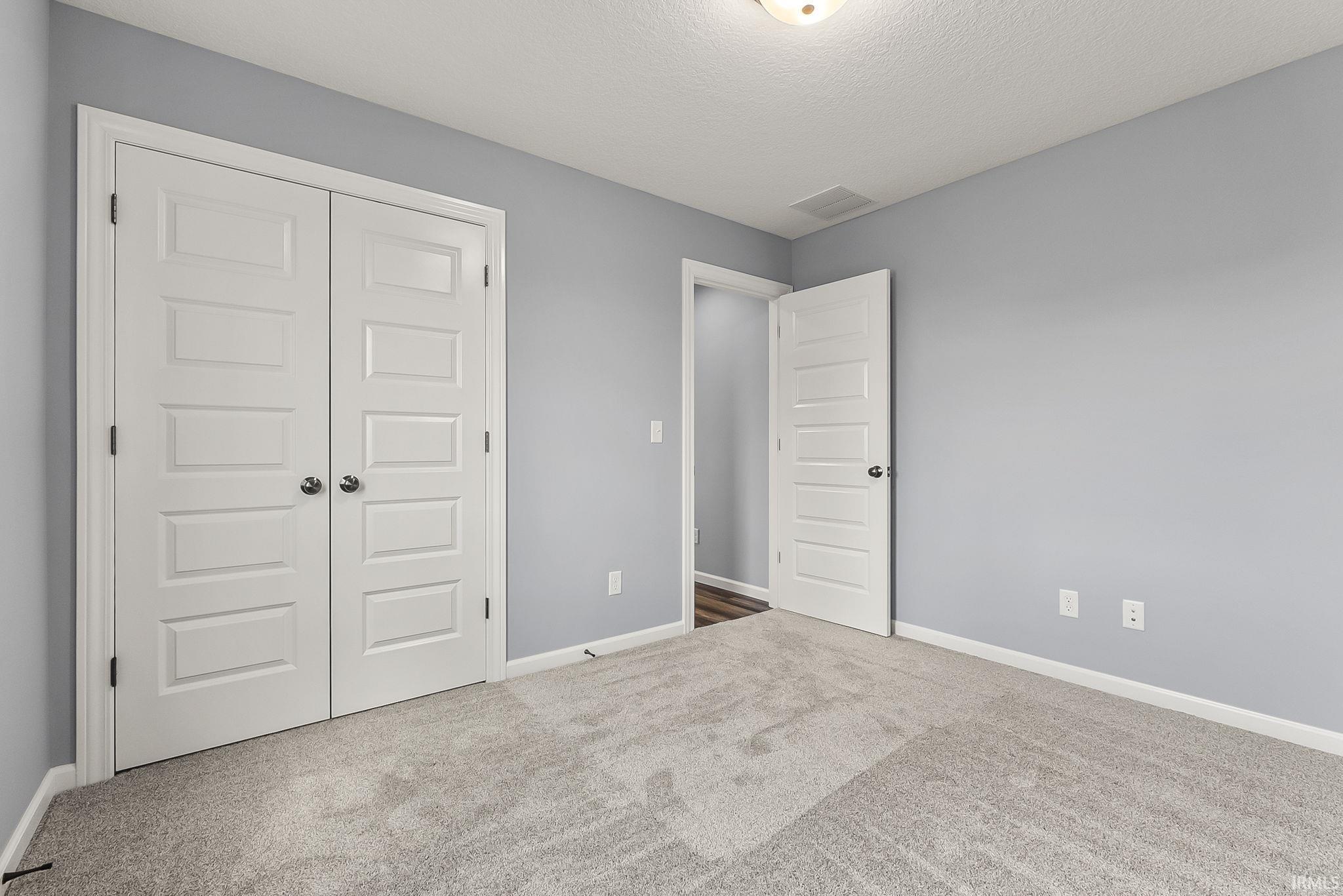 Unfurnished bedroom with carpet flooring, a closet, and a textured ceiling