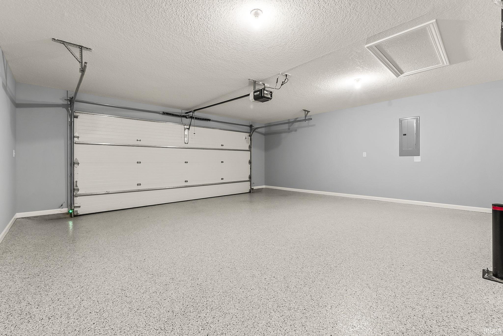 Garage featuring electric panel and baseboards