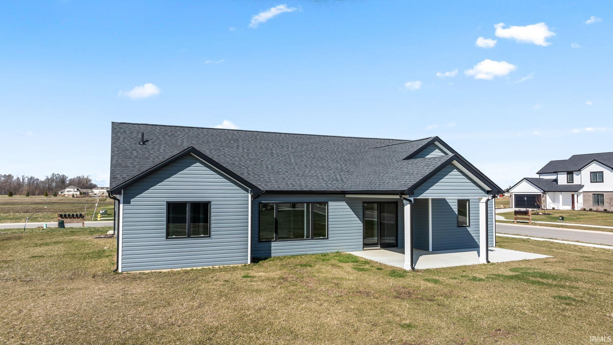 Back of house with a yard, a shingled roof, and a patio area