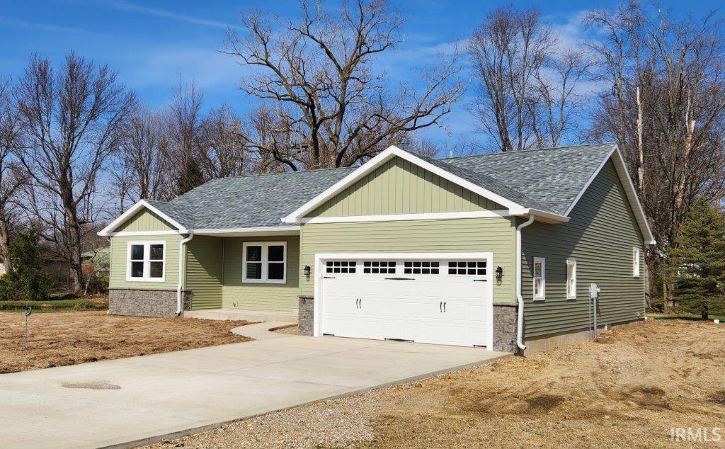 View of front of house with an attached garage, concrete driveway, and a shingled roof