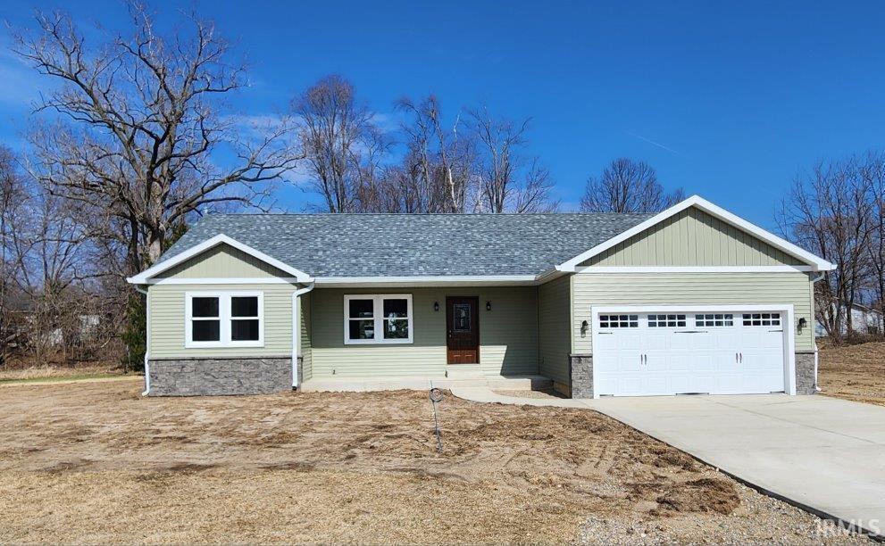 View of front of home with a porch, a garage, stone siding, and concrete driveway