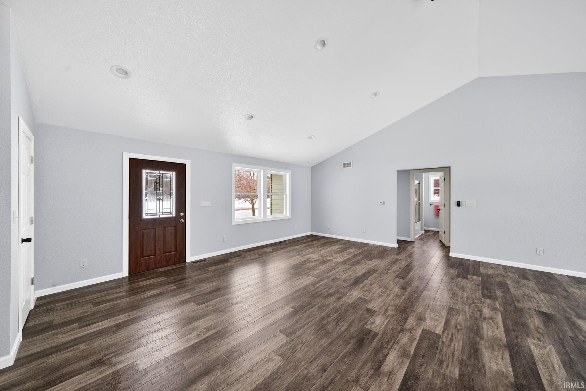 Foyer with dark wood-type flooring and vaulted ceiling